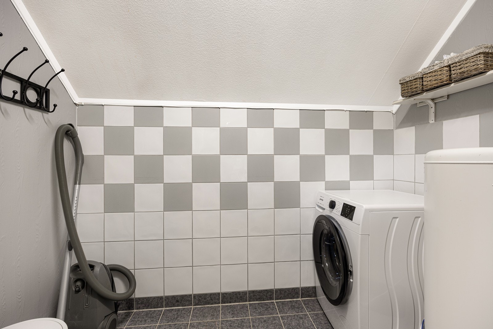 Boden ved vindfanget har flislagt gulv og opplegg for vaskemaskin. Boden er ikke bygget som våtrom og det er ikke søkt bruksendring for arealet. Galleribilde