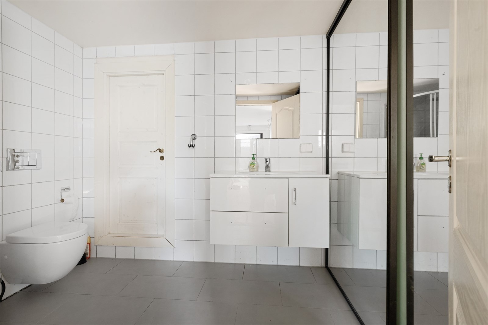Badet i hybel med skyvedørsgarderobe- installert dusjhjørne, vegghengt toalett og baderomsinnredning - opplegg til vaskemaskin Galleribilde