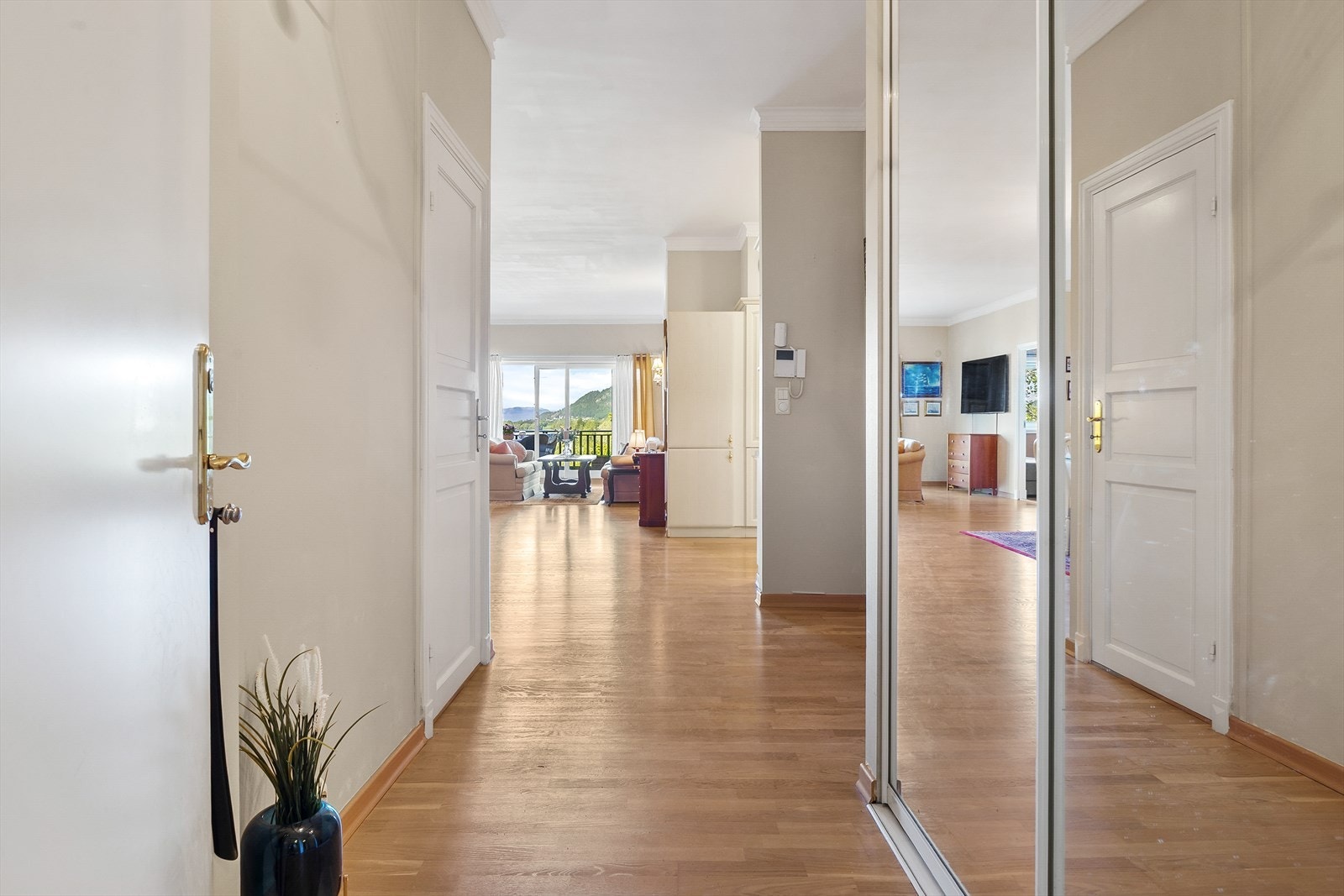 Entreen har et innbydende og lyst interiør med parkettgulv og integrert skyvedørsgarderobe med speilfronter. Galleribilde