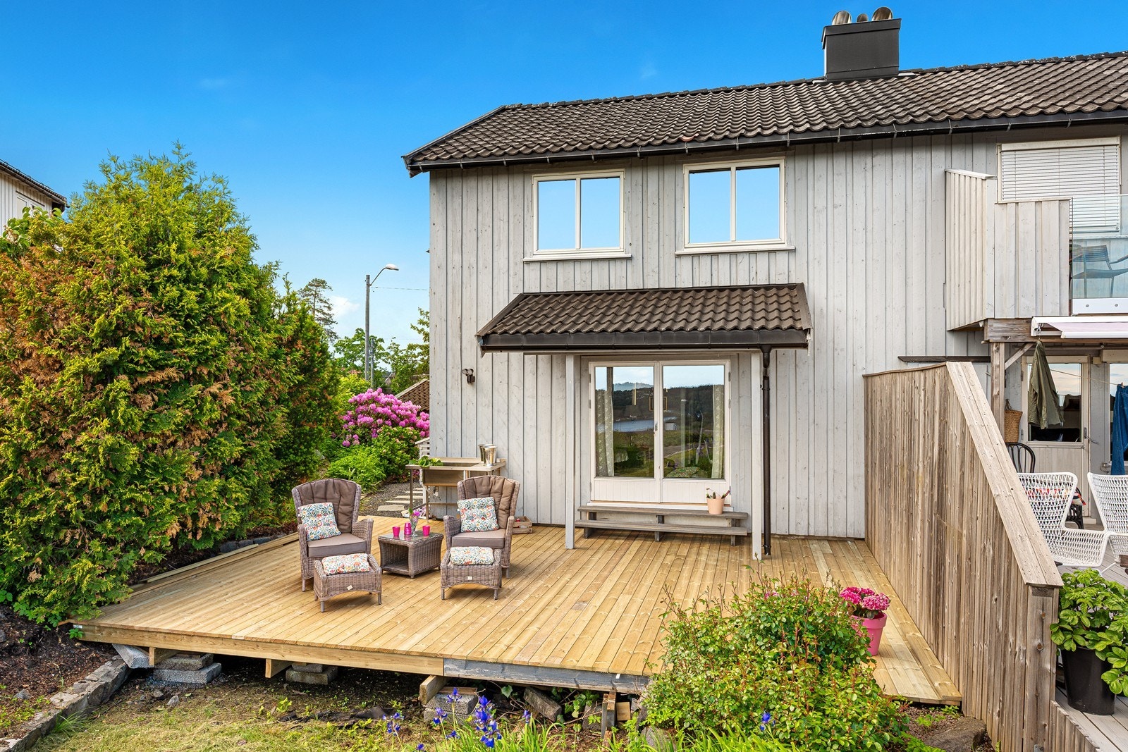 Pent opparbeidet tomt med romslig ny platting, plen og beplantet med busker og blomster. Galleribilde