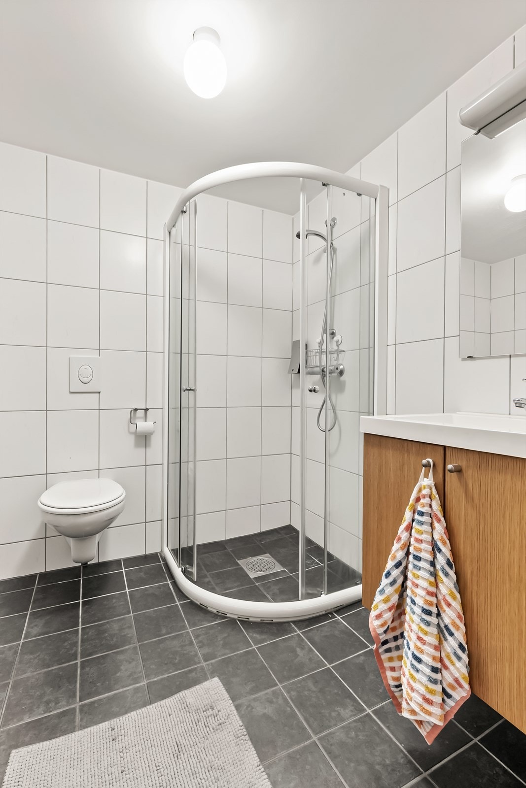 Badet er innredet med toalett, dusj på gulv og servant. Galleribilde