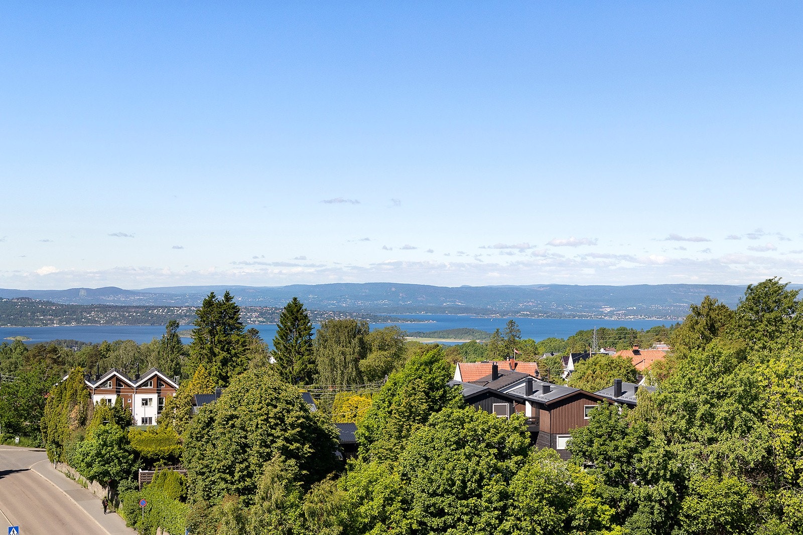 Åpent utsyn over grønne omgivelser og fjorden i horisonten. Galleribilde