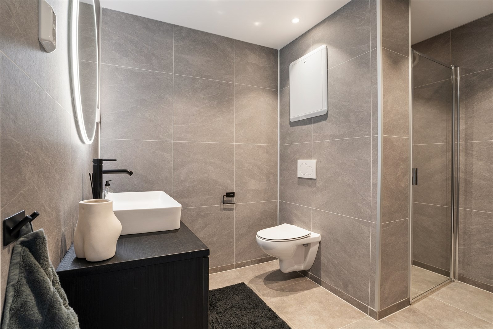 Badet fra 2021 fremstår moderne og delikat med flislagte overflater og behagelig gulvvarme. Her er det lagt vekt på både funksjonalitet og estetikk. Galleribilde