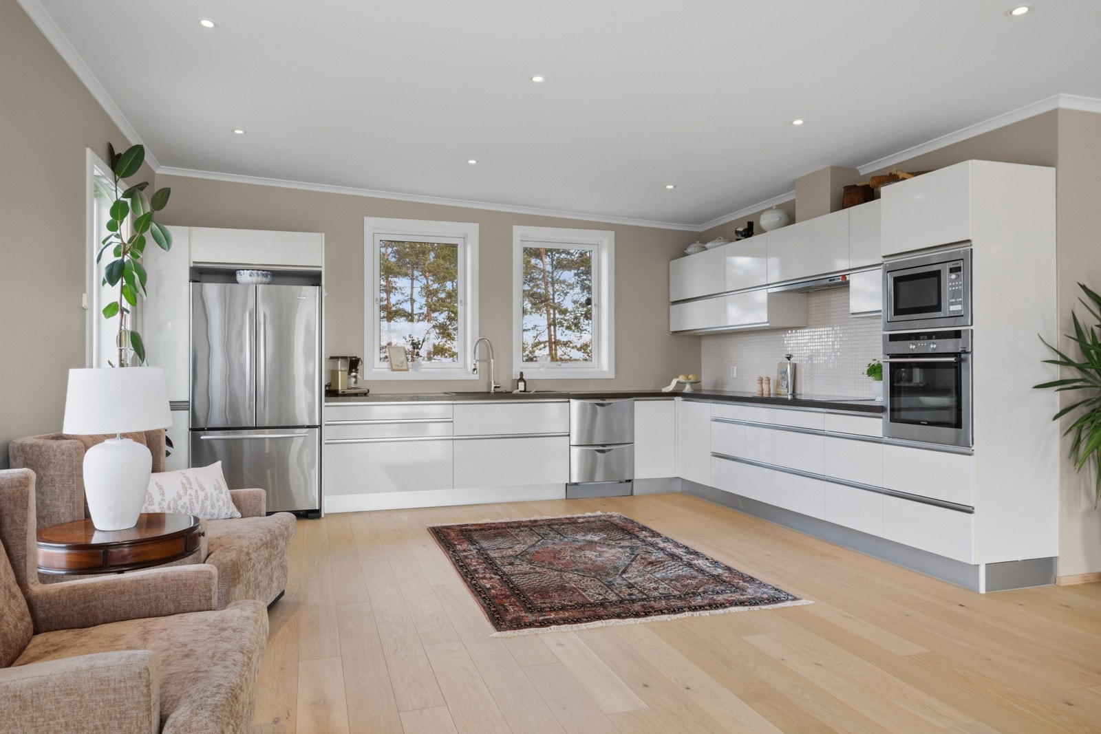 Kjøkkeninnredningen er fra Schmidt og har hvite, slette fronter med sølvfargede grep, kombinert med grå sokkel og sorte benkeplater av laminat. Galleribilde