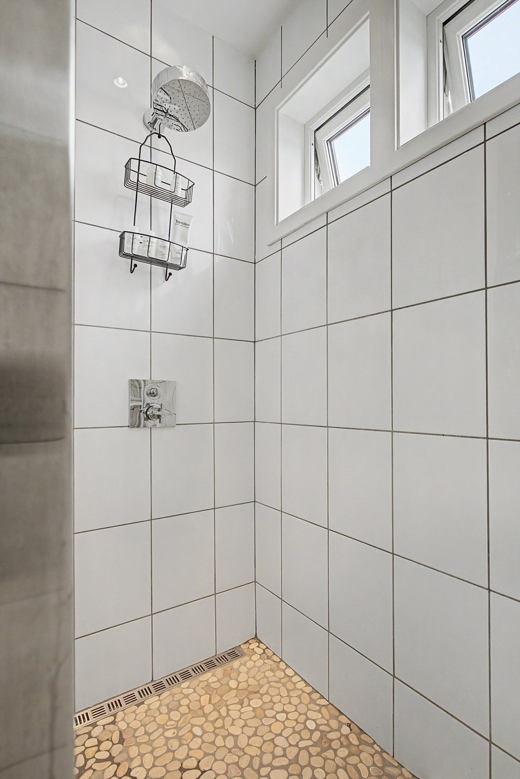 Bad på loft har malte takflater. Flislagte vegger og gulv. Baderomsinnredning, vegghengt WC og dusjnisje med glassbyggerstein. Galleribilde