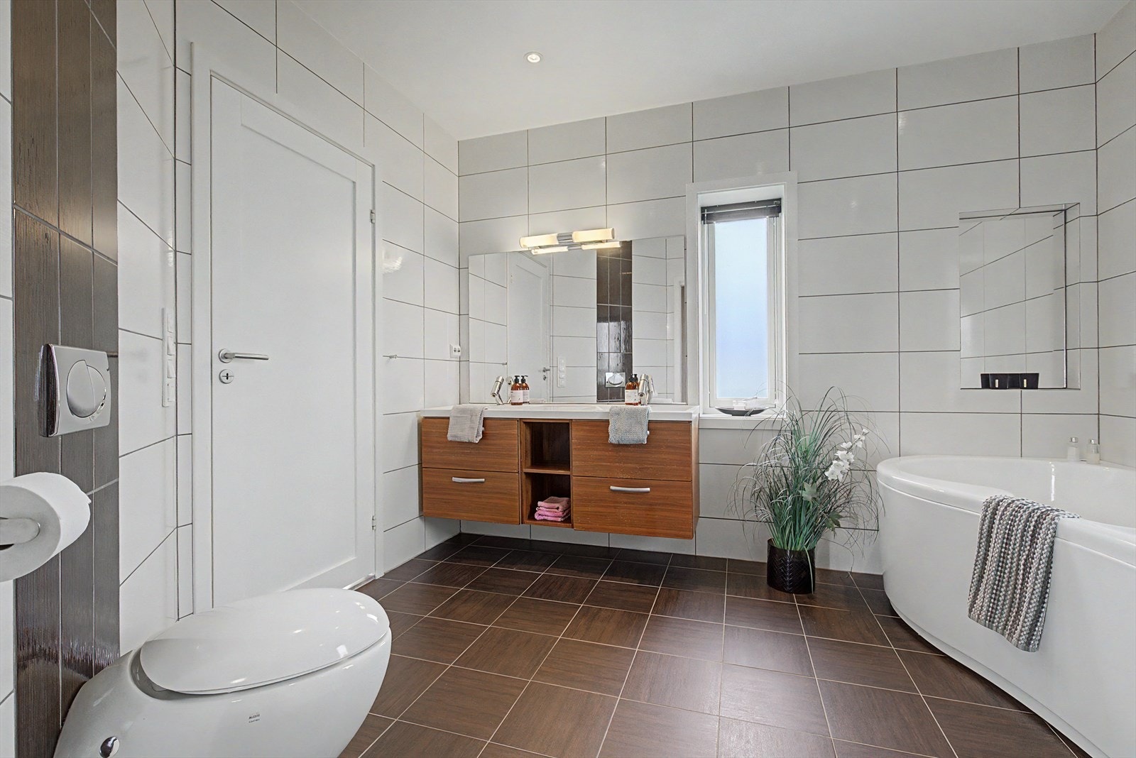 Badet i hovedetasjen har malte takplater. Flislagte vegger og gulv. Baderomsinnredning, vegghengt WC, dusjkabinett og badekar. Galleribilde