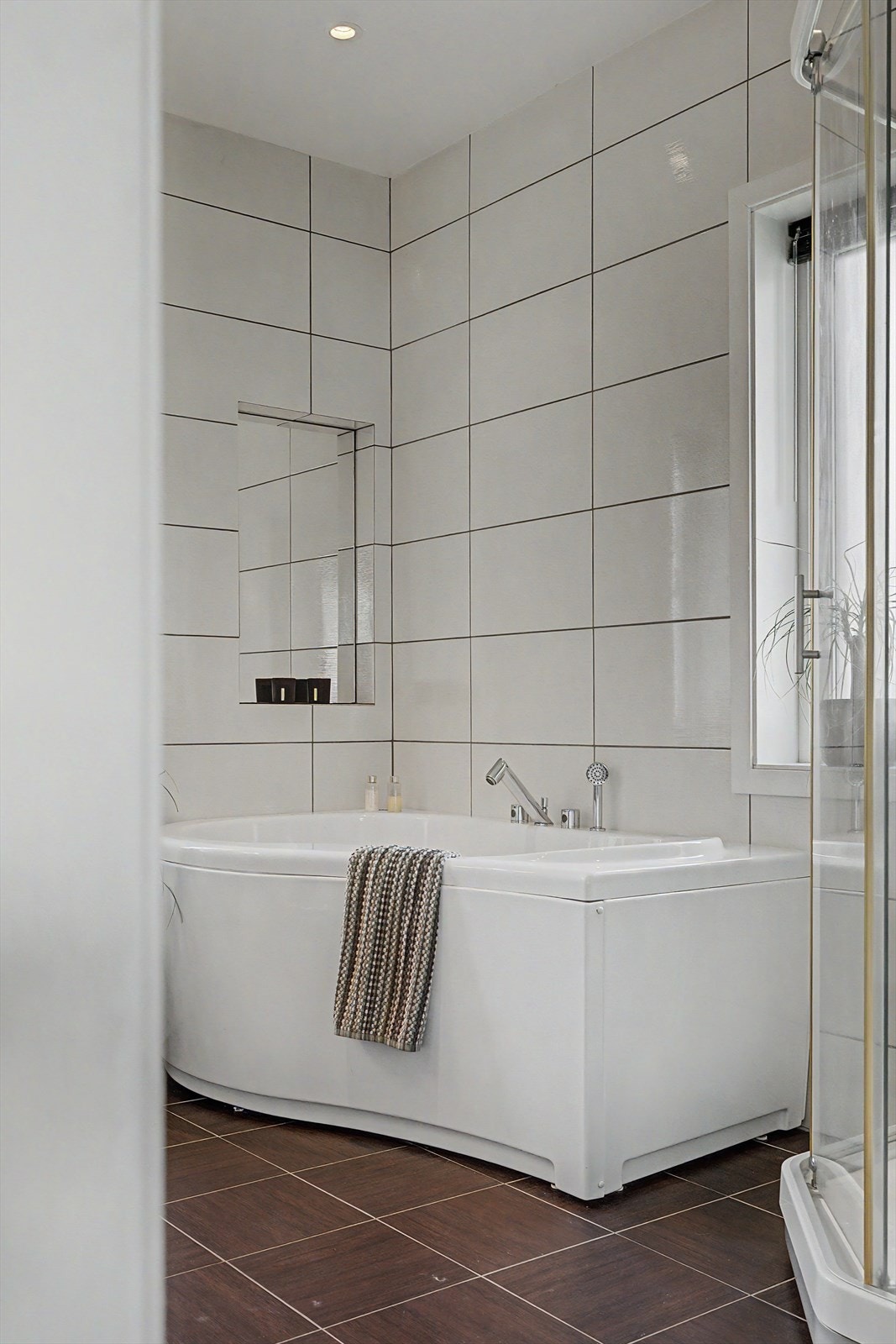 Badet i hovedetasjen har malte takplater. Flislagte vegger og gulv. Baderomsinnredning, vegghengt WC, dusjkabinett og badekar. Galleribilde