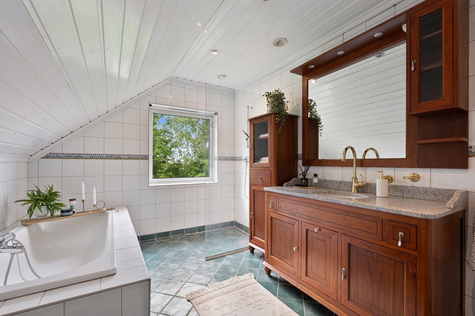 Badet i 2. etasje har flislagt gulv med gulvvarme, flislagte vegger og malt panel i himlingen. Innredningen består av servant med innredning, klosett, innmurt badekar og dusjnisje. Galleribilde