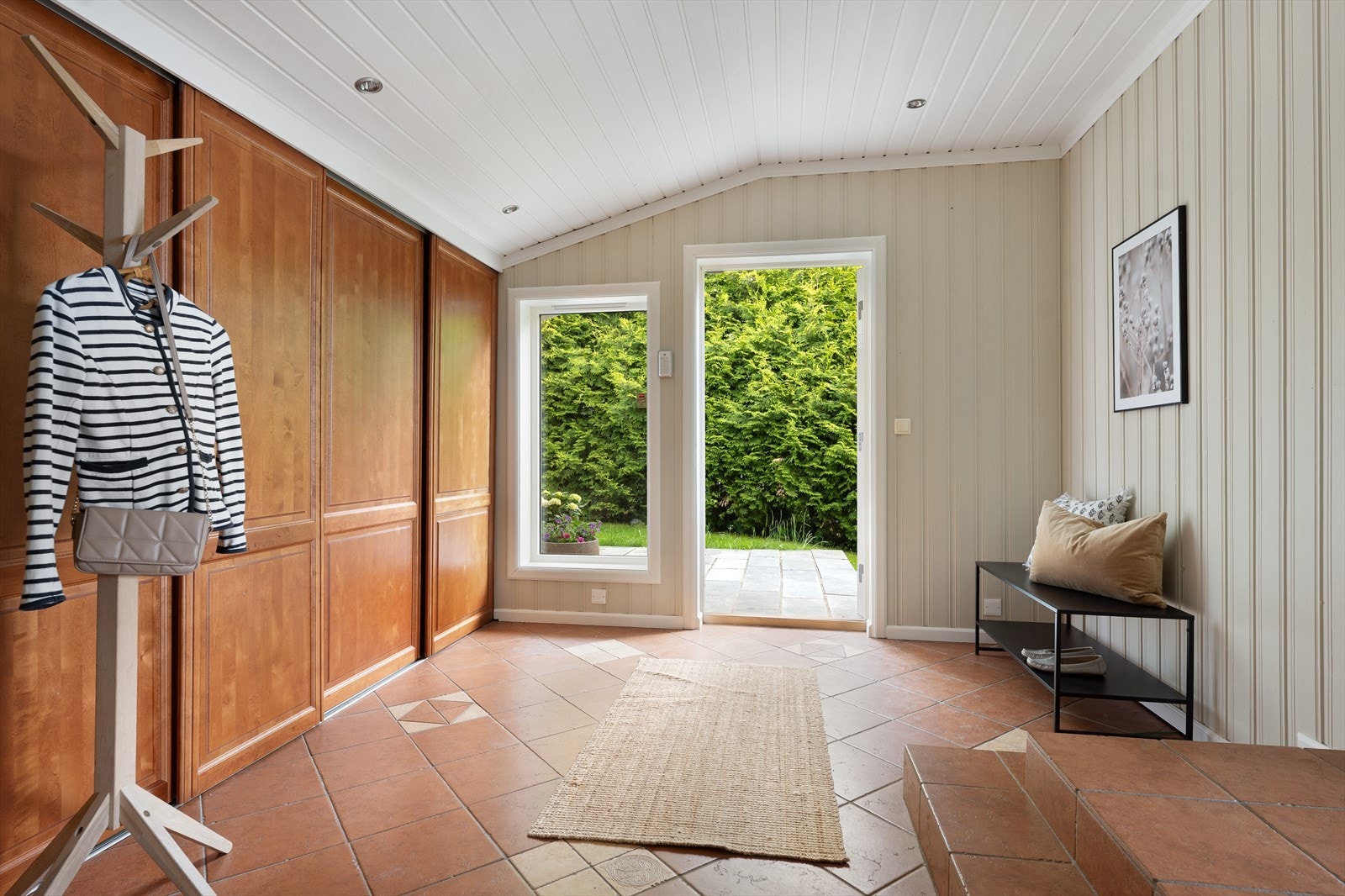 Boligens hoveddel har en romslig hall. Langs den ene veggen er det etablert en stor skyvedørsgarderobe som gir rikelig med oppbevaringsplass til yttertøy, sko og annet utstyr. Galleribilde