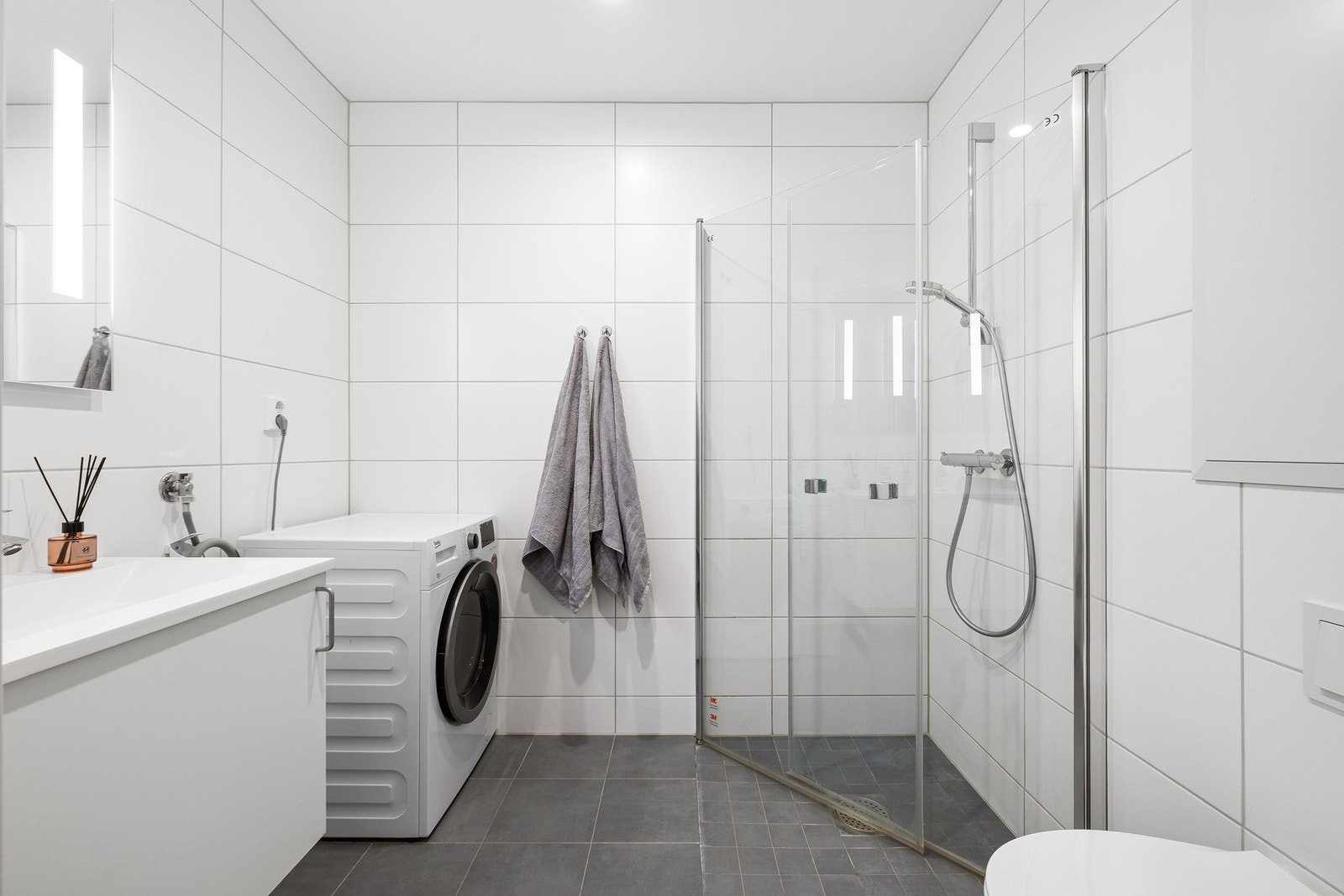 Lyst baderom med store og lekre fliser på vegg og gulv. Badet holdes varmt ved bruk av elektriske varmekabler. Galleribilde