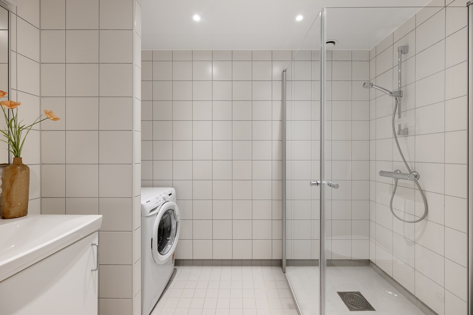 Flislagt bad med vannbåren gulvvarme, dusjhjørne med glassvegger og opplegg for vaskemaskin. Galleribilde