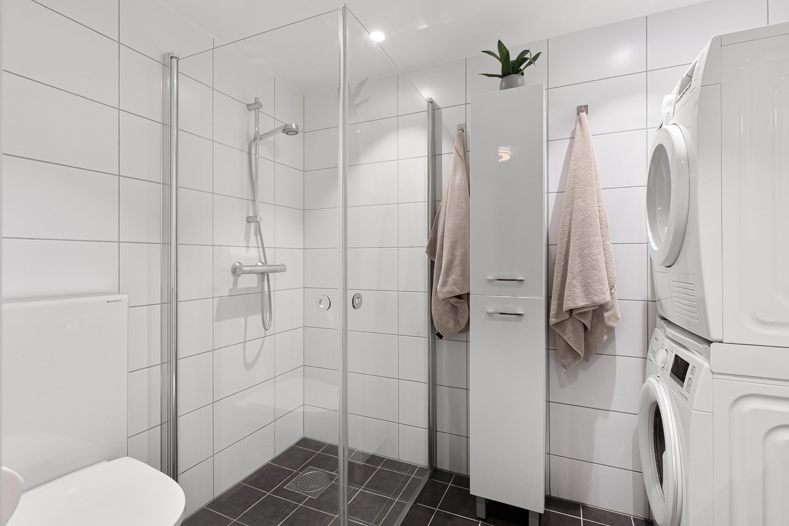Badet har flislagt gulv med varme, downlights og opplegg for vaskemaskin og tørketrommel Galleribilde