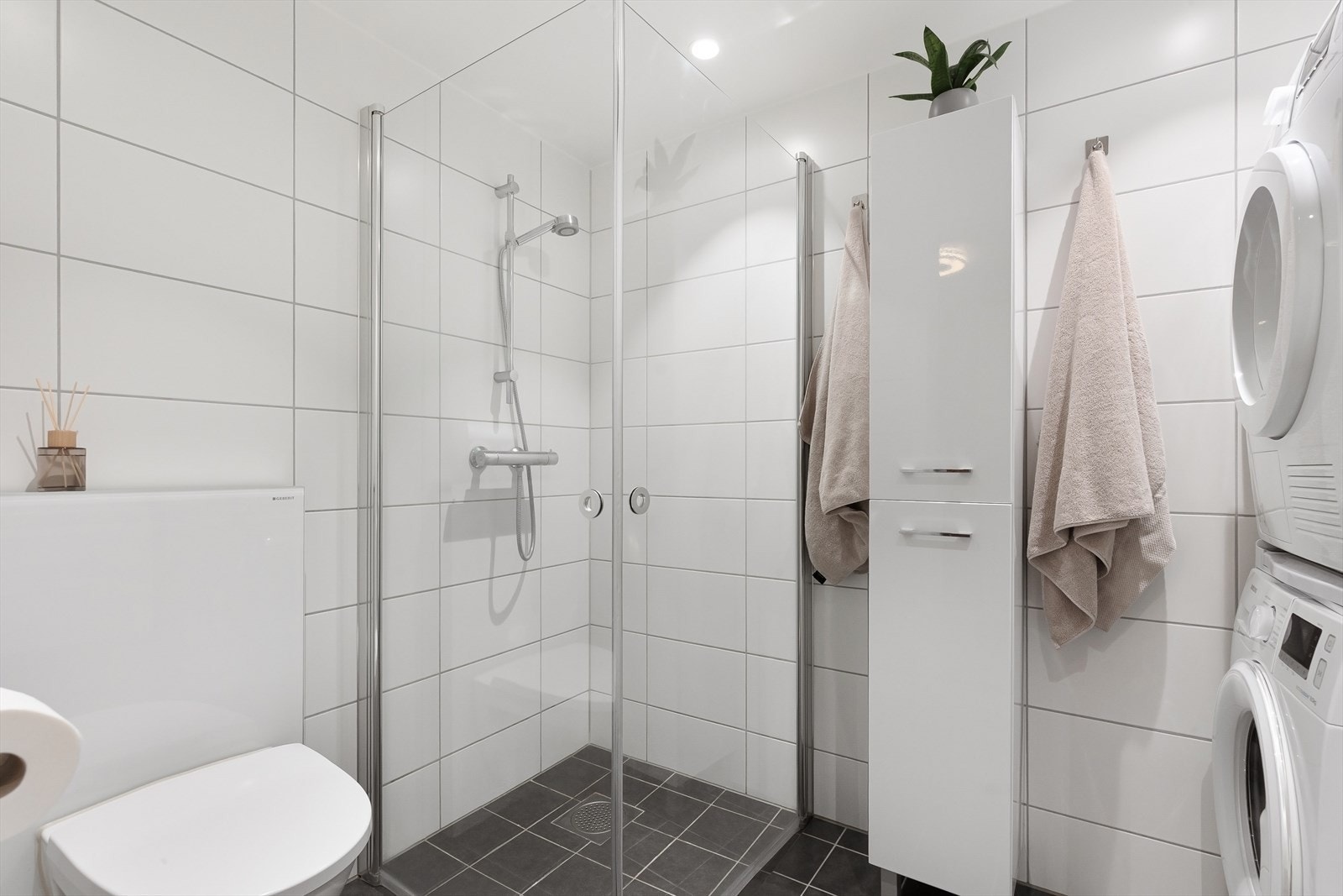 Badet har flislagt gulv med varme, downlights og opplegg for vaskemaskin og tørketrommel Galleribilde