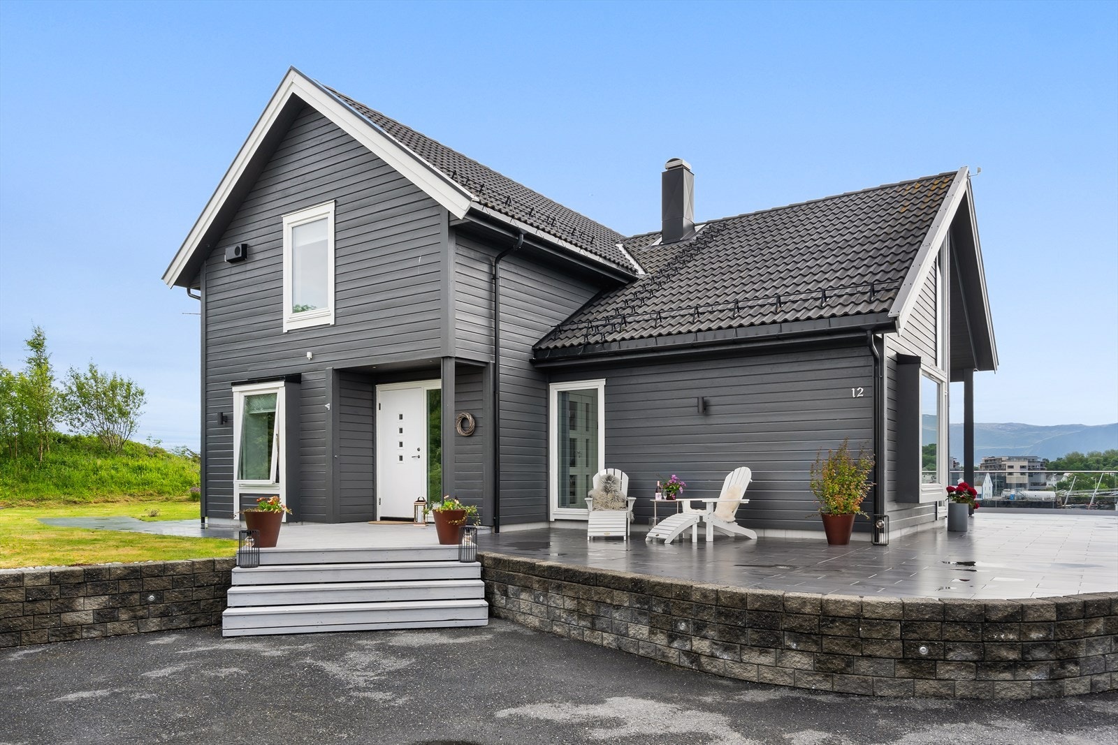 Et gjennomført og flott parti mellom innkjørselen, garasjen og inngangspartiet. Mur med integrert belysning og en plassbygd tretrapp leder opp til tredekket ved inngangspartiet. Galleribilde
