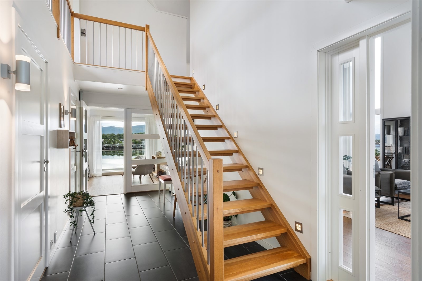 Innbydende entré og hall med god takhøyde, moderne materialvalg og en stilren trapp som setter preg på boligen. Galleribilde