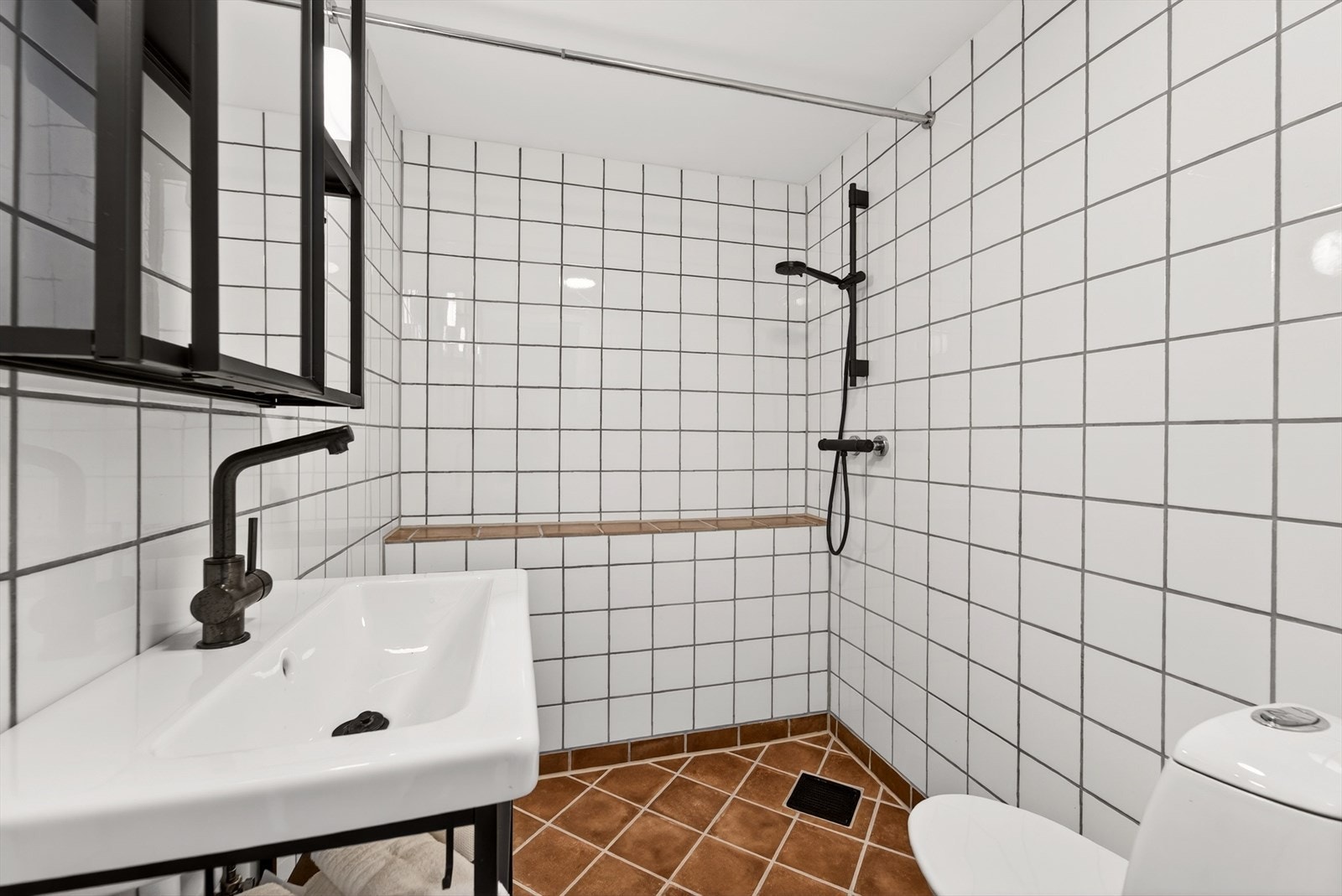 Pent bad med fliser på gulv og vegger. Innredet med baderomsinnredning, toalett og dusjløsning. Varmekabler i gulv. Galleribilde