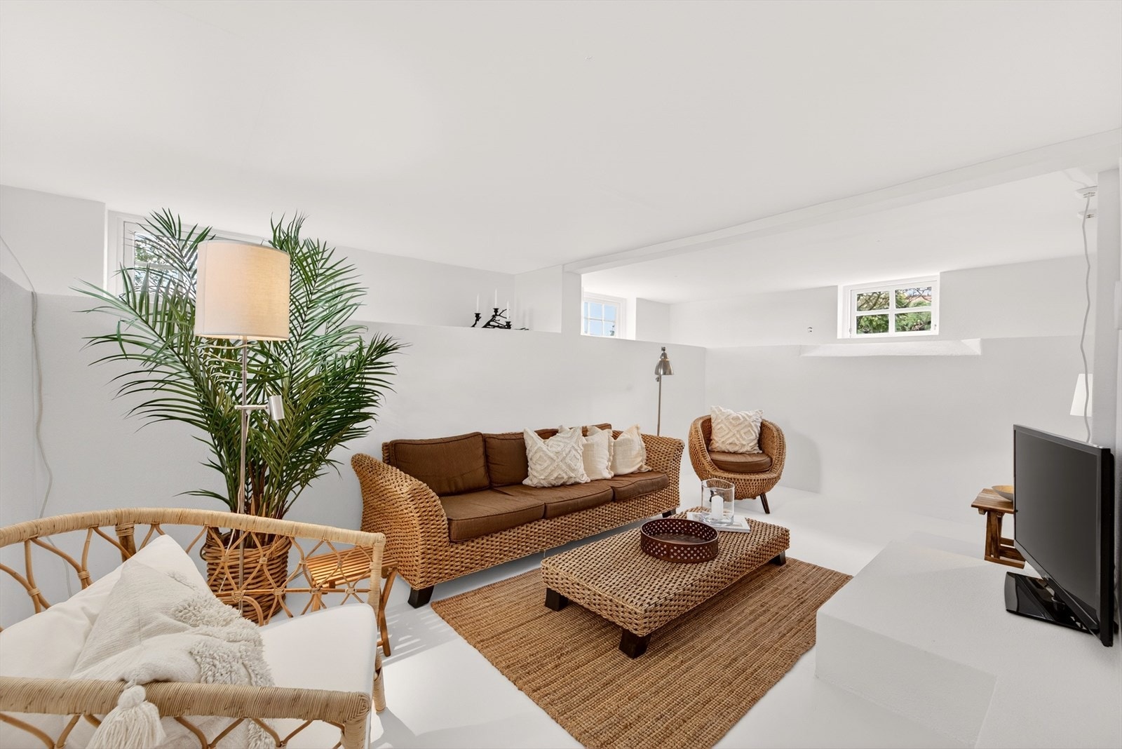 Lys og luftig kjellerstue med en rolig og avslappende atmosfære. Hvite overflater gir et rent og minimalistisk uttrykk, samtidig som de reflekterer lyset og gjør rommet åpent og innbydende. Galleribilde