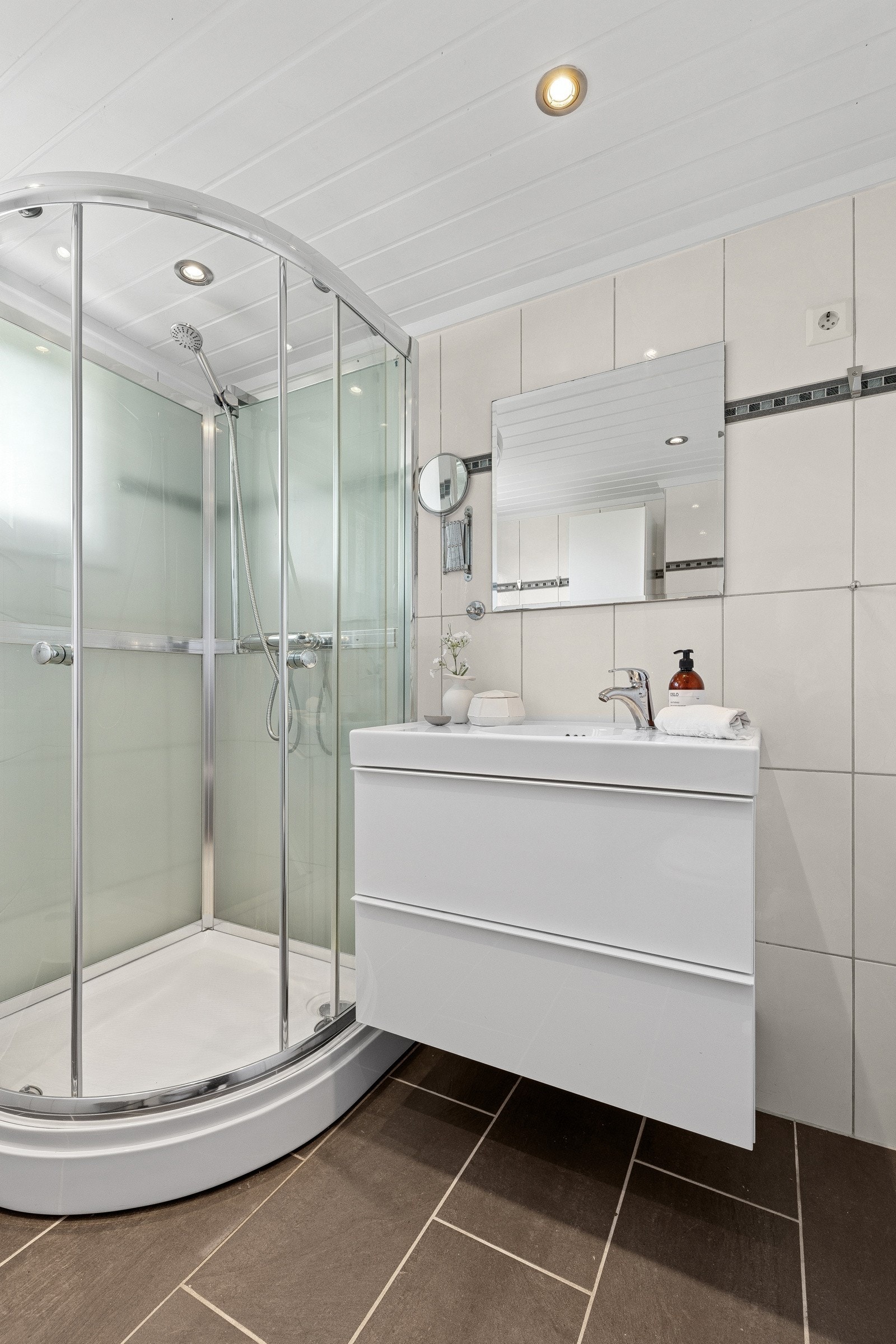 Badet i kjelleren består av speil, servant med seksjon, veggmontert toalett og dusjkabinett. Galleribilde