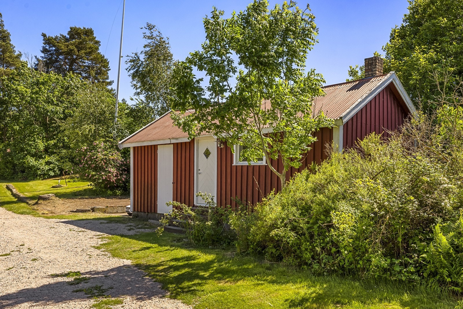 Eldre bod med stående trekledning og saltak tekket med stålplater. Galleribilde