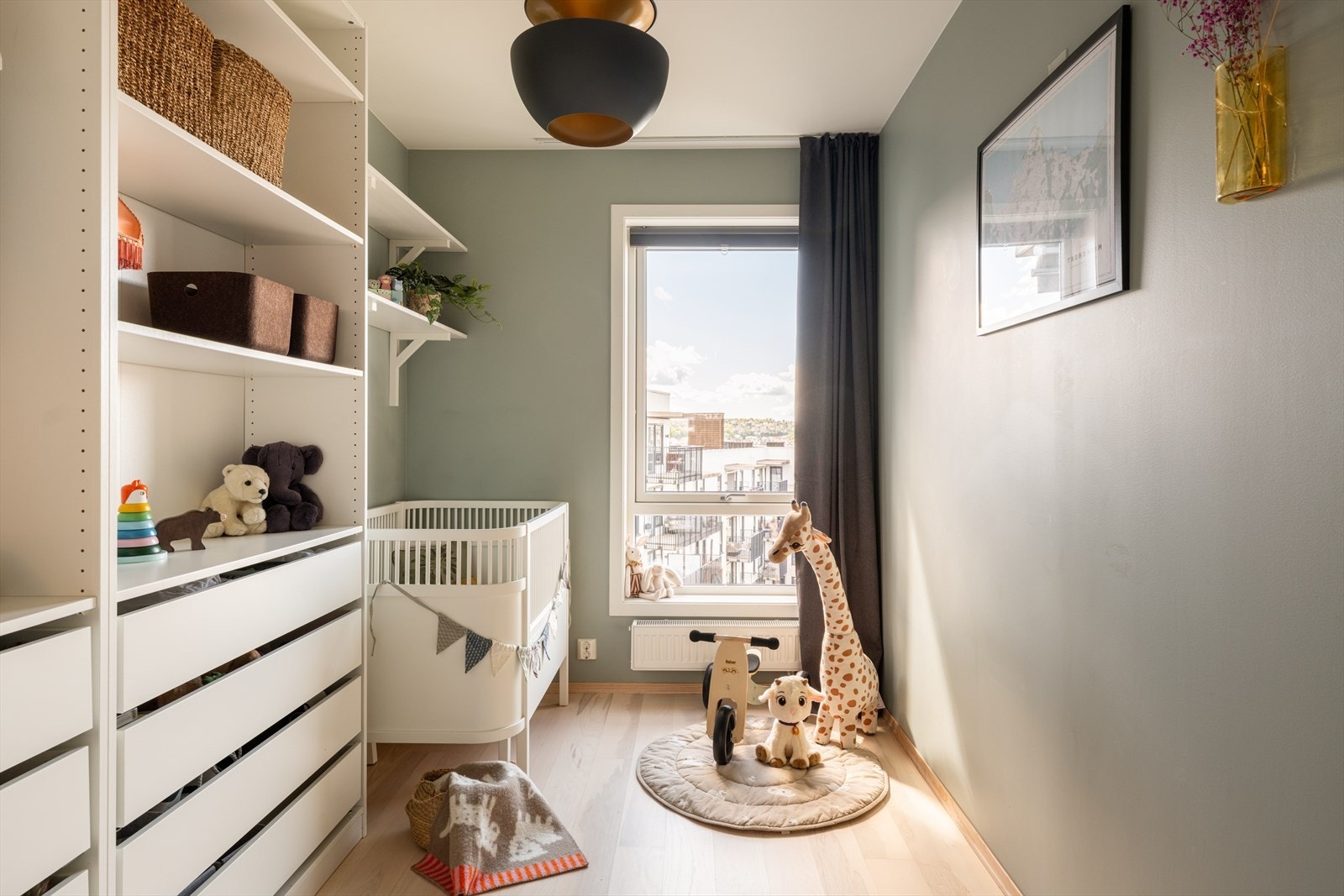 Barnerommet har en lun atmosfære med duse fargetoner og fine lysforhold fra det store vinduet. Galleribilde