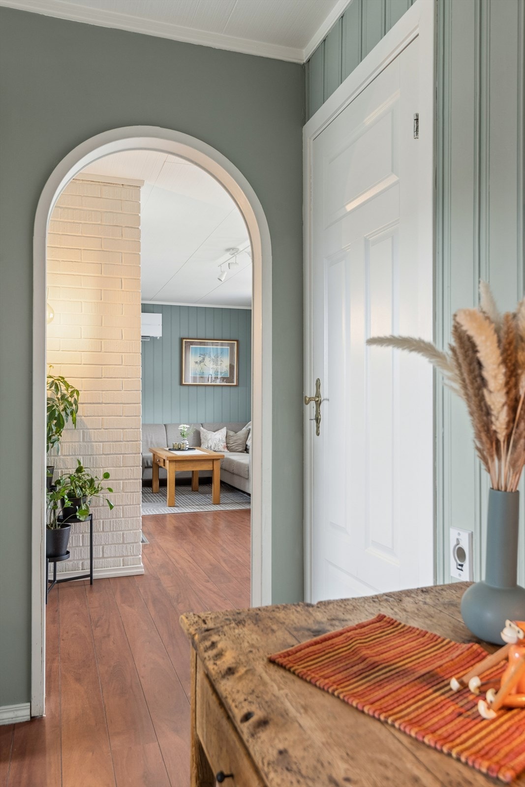 En buet åpning fører fra gangen og inn til stuen. Galleribilde