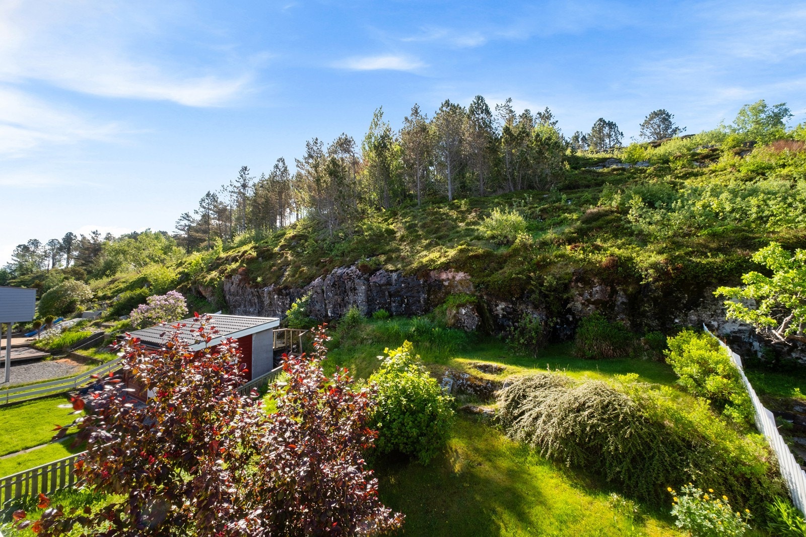 På sørsiden av huset er det opparbeidet hage, med plen og beplantning, og med trapptilgang fra den sørvendte verandaen Galleribilde