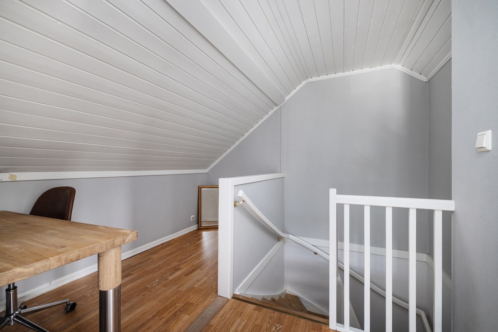 Trappen i treverk forbinder de to etasjene, med rekkverk på én side og håndløper på veggen. Galleribilde
