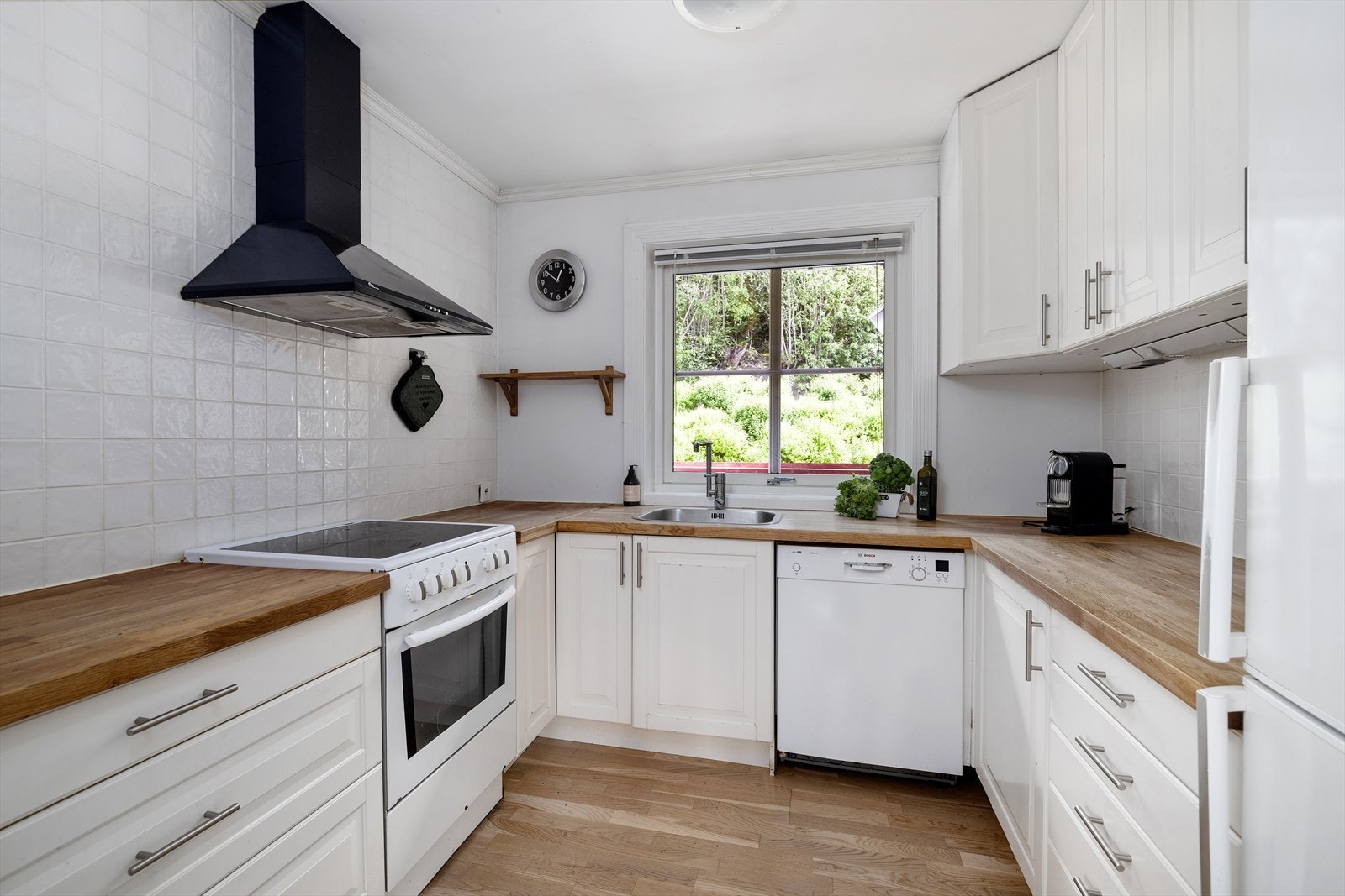 Kjøkkeninnredning fra Ikea med profilerte fronter og benkeplate i heltre. Det er opplegg for vaskemaskin. Galleribilde