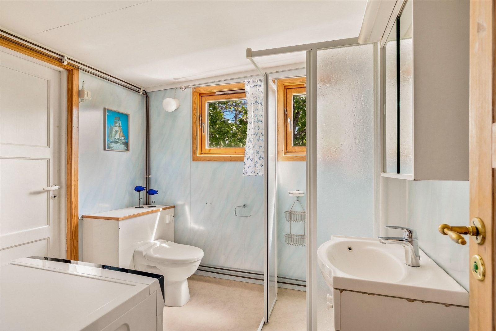 Enkelt bad med wc, servant i seksjon, dusjhjørne og opplegg til vaskemaskin. Fra badet er det også utgang. Galleribilde