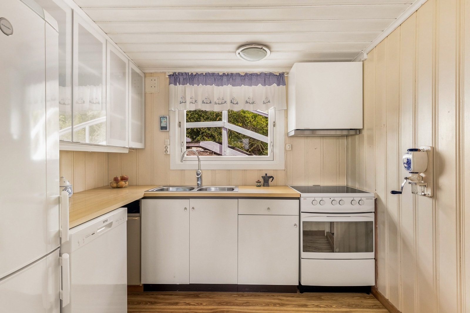 Kjøkken med enkel innredning med slette fronter, ventilator, stålvask. Komfyr, oppvaskmaskin, kjøl- og fryseskap medfølger i handelen. Galleribilde