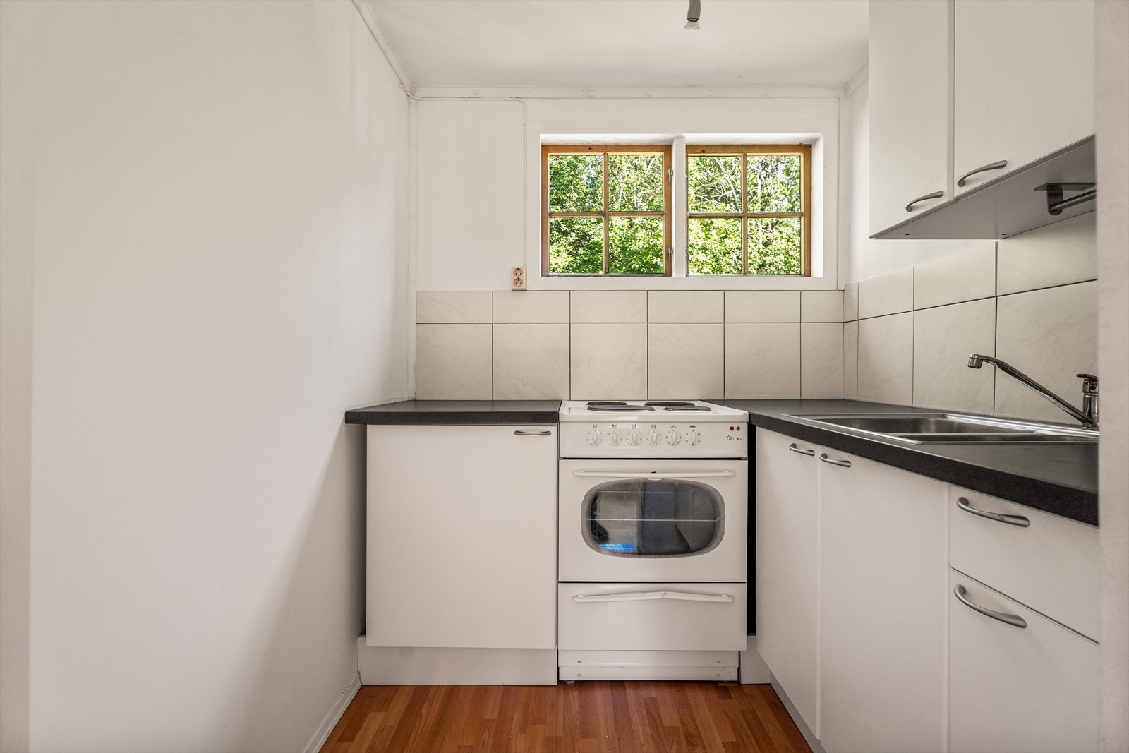 Kjøkkeninnredning fra Ikea med hvite, slette fronter, laminatbenkeplate og fliser over benk. Galleribilde