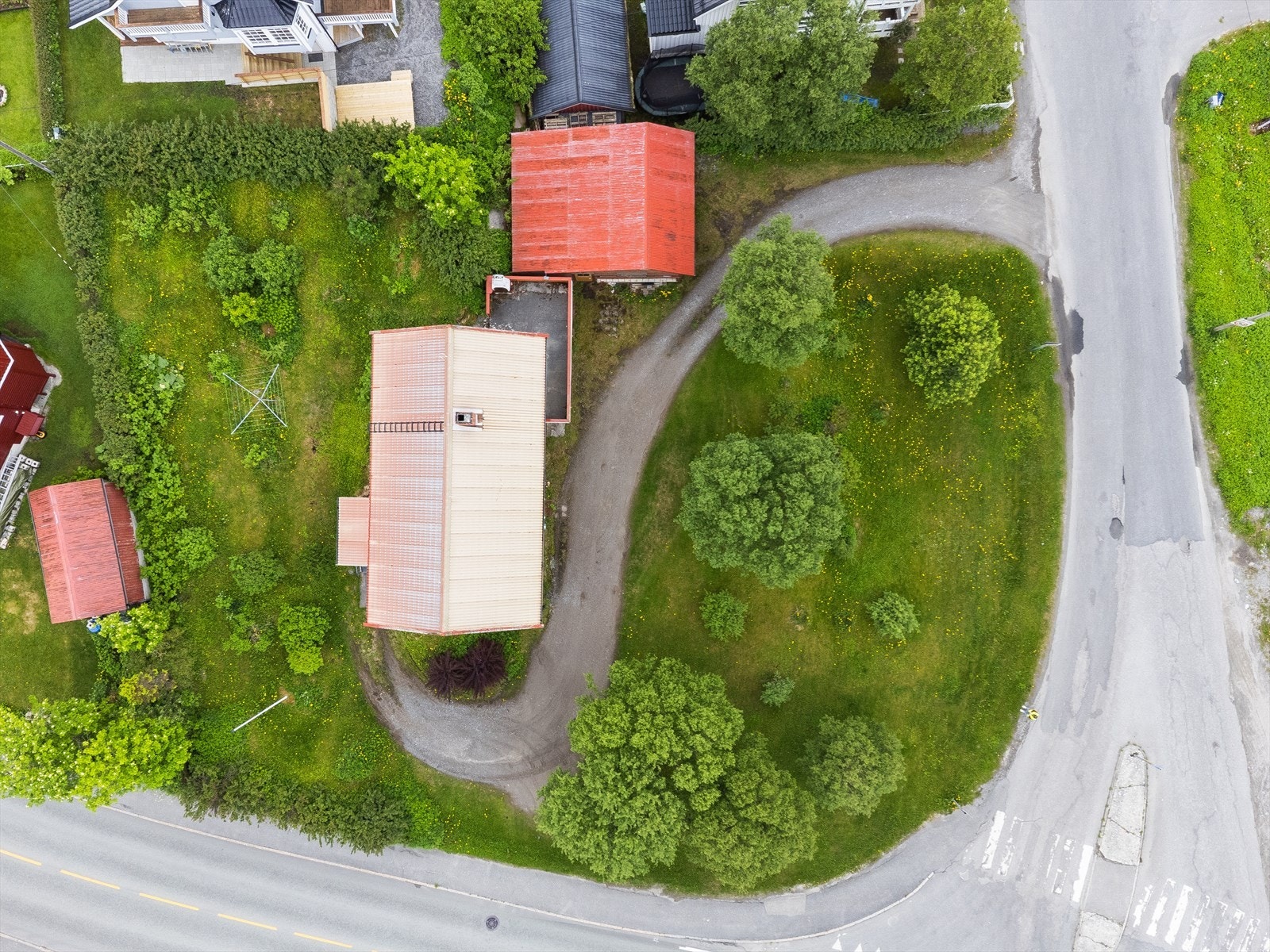 Tomten er opparbeidet med plen, busker og trær, samt gruset innkjøring med parkeringsmuligheter. Galleribilde