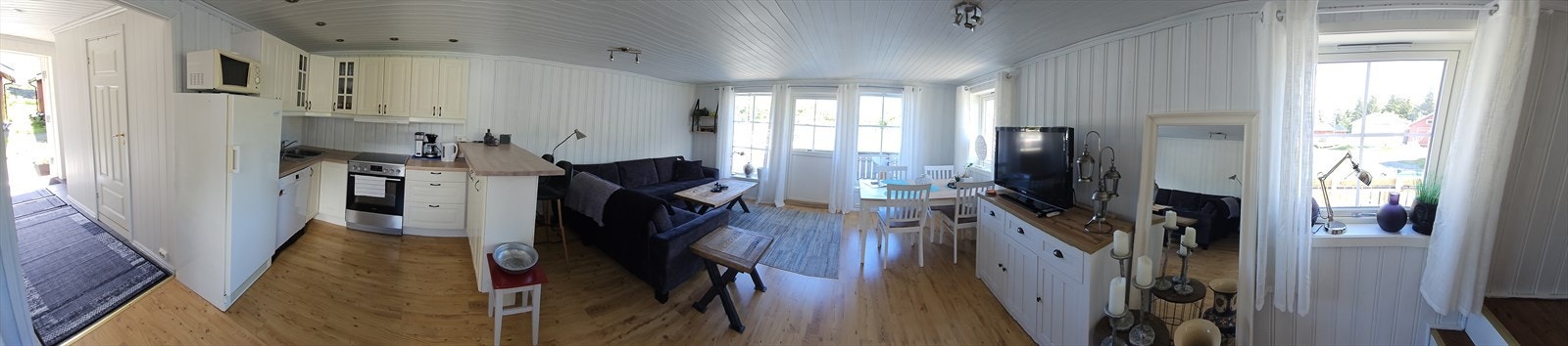 Stue med malte trepanel og laminatgulv gir en praktisk og gjennomgående stil. Galleribilde