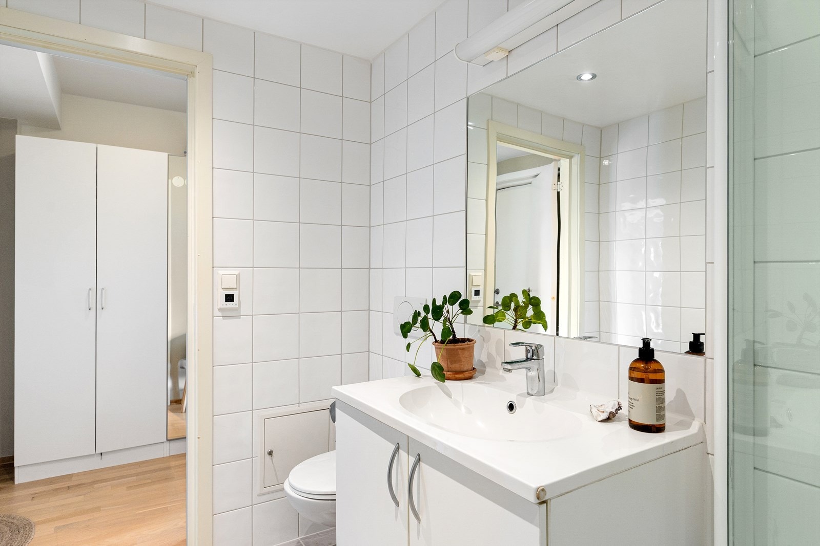 Badet er innredet med vegghengt klosett, servant nedfelt i baderomsinnredning og dusjhjørne med svingbare glassdører. Det er opplegg for vaskemaskin. Galleribilde
