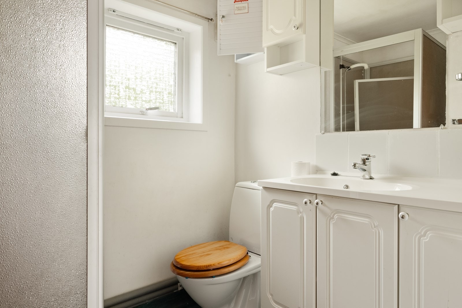 Badet har belegg på gulv, malte vegger og plater i himling, og er utstyrt med toalett, dusjkabinett og servant. Galleribilde