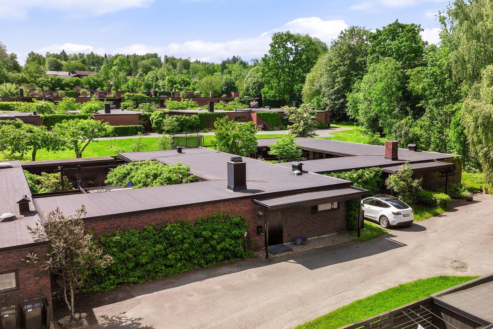Husenes lave profil og teglfasade ønsker deg velkommen. Det er plass for parkering utenfor boligen, og det er montert elbil lader. Galleribilde