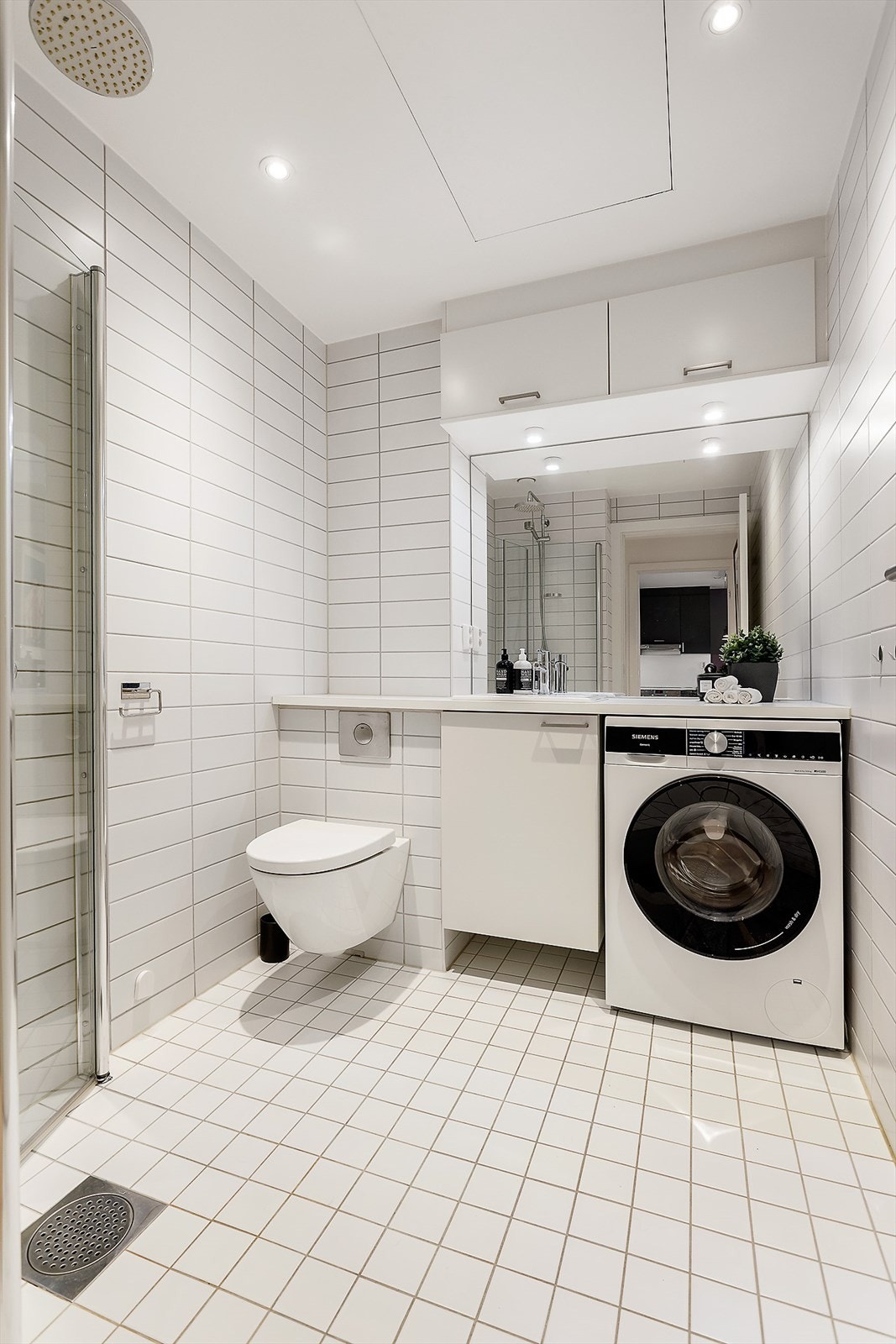 Badet er innredet med servantskap, dusjhjørne, toalett og opplegg for vaskemaskin. Galleribilde
