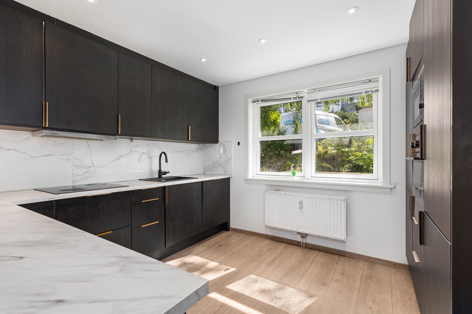 Kjøkkenet ligger i tilknytning til stuen og er utstyrt med innredning med glatte fronter, laminat benkeplate og hvitevarer bestående av kjøl-/fryseskap, oppvaskmaskin, platetopp, stekeovn og mikroovn. Galleribilde