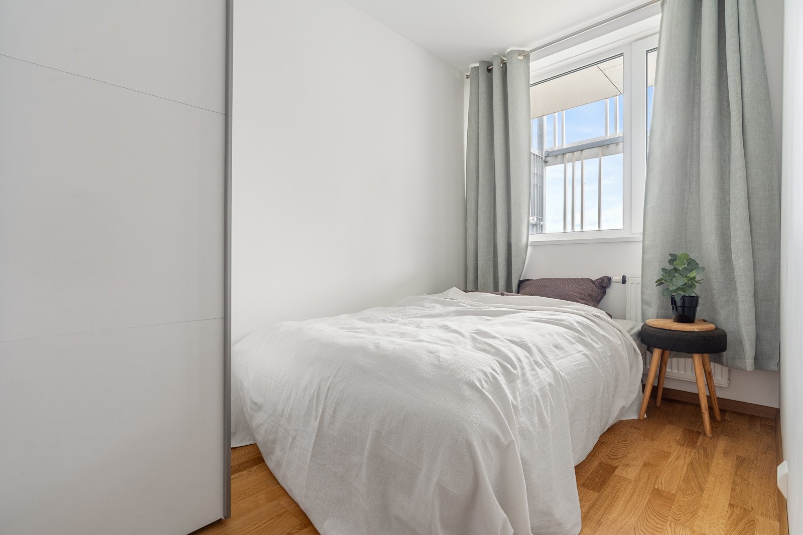 Soverom 2 med parkettgulv, vegger malt i lyse farger og skyvedørsgarderobe