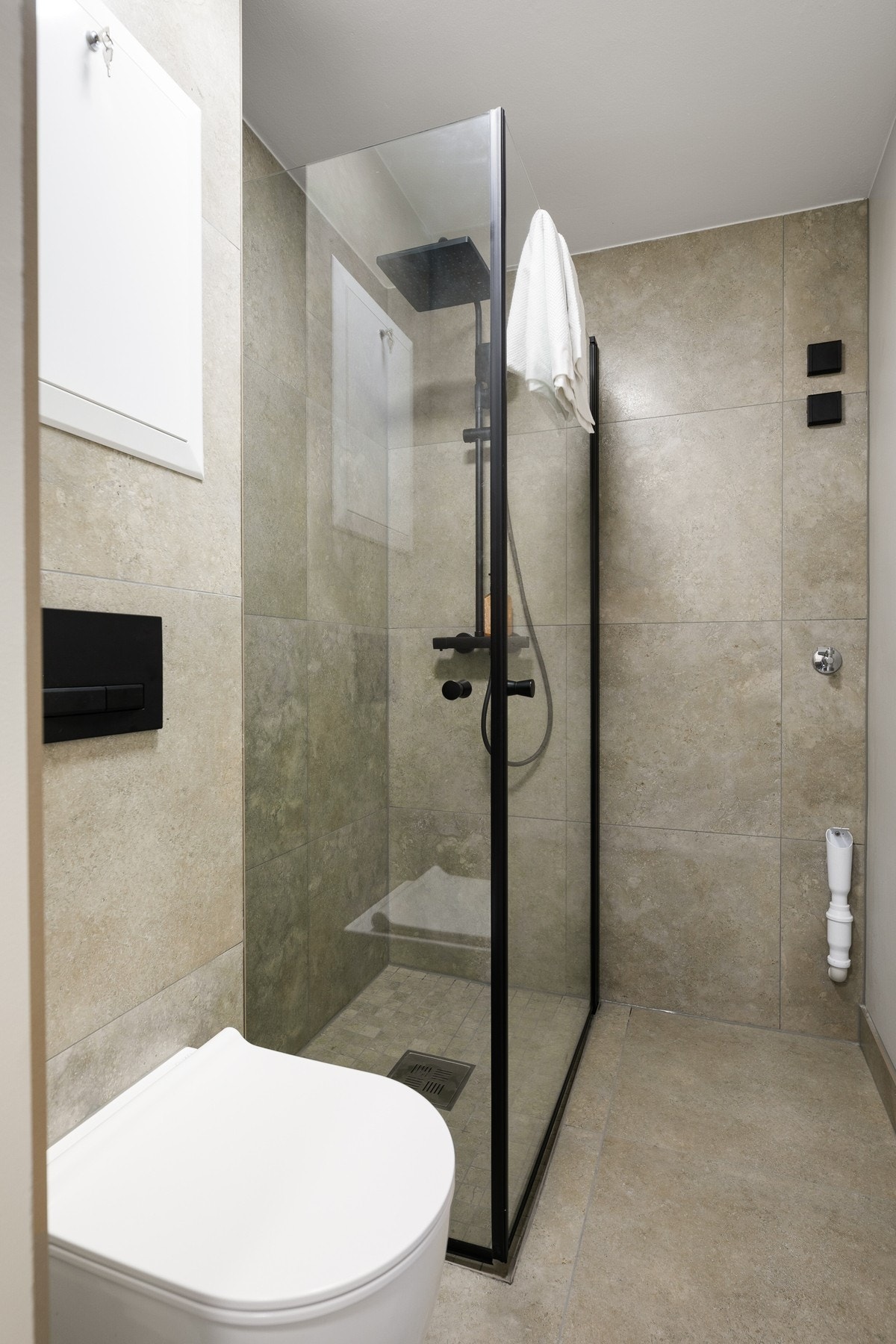 Badet er utstyrt med dusjhjørne med glassdører, vegghengt toalett, moderne baderomsinnredning med servant og speil med integrert belysning. Galleribilde
