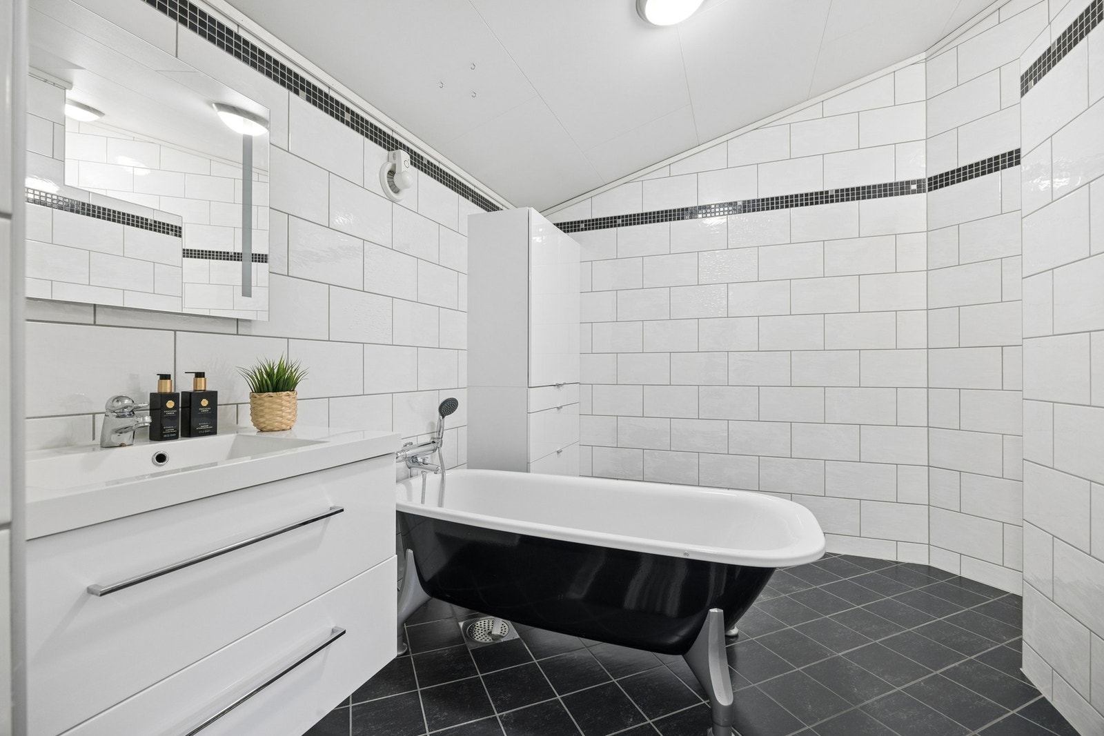 Badet har en god størrelse og tilbyr både komfort og funksjonalitet med frittstående badekar og praktiske oppbevaringsløsninger. Galleribilde
