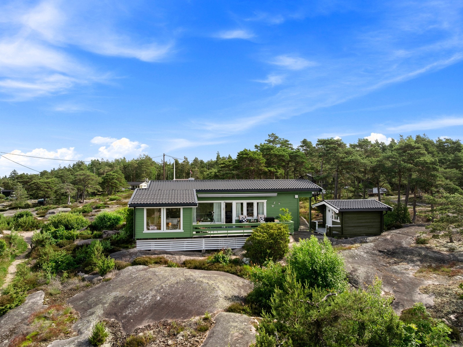 Hytta ligger flott til på svabergtomt, med grønn fasade som glir fint inn i de naturskjønne omgivelsene. Taket ble lagt om i 2015 og fremstår i god stand. Galleribilde
