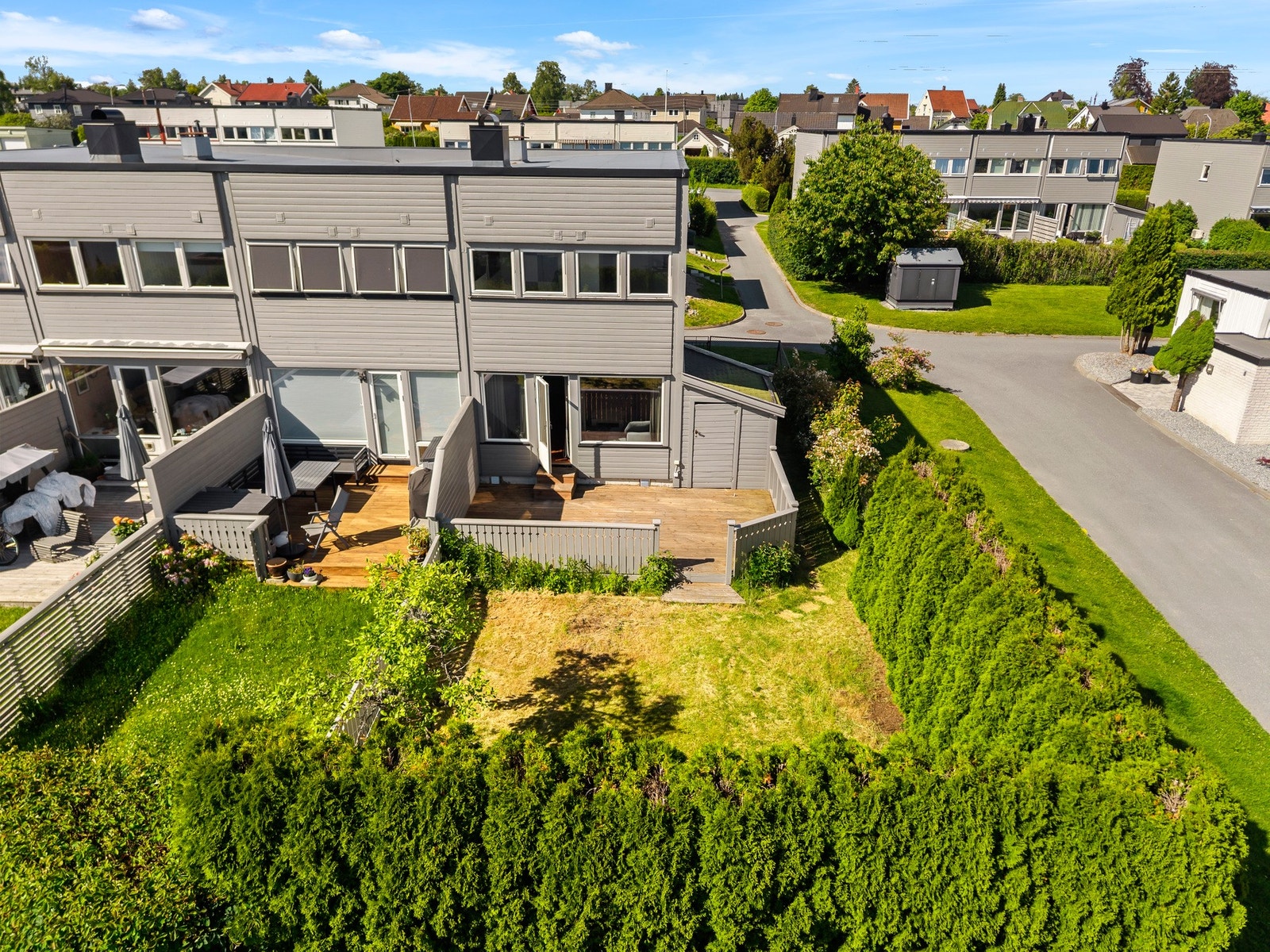 Et stålgjerde og en tujahekk skiller tomten fra internveien. Galleribilde