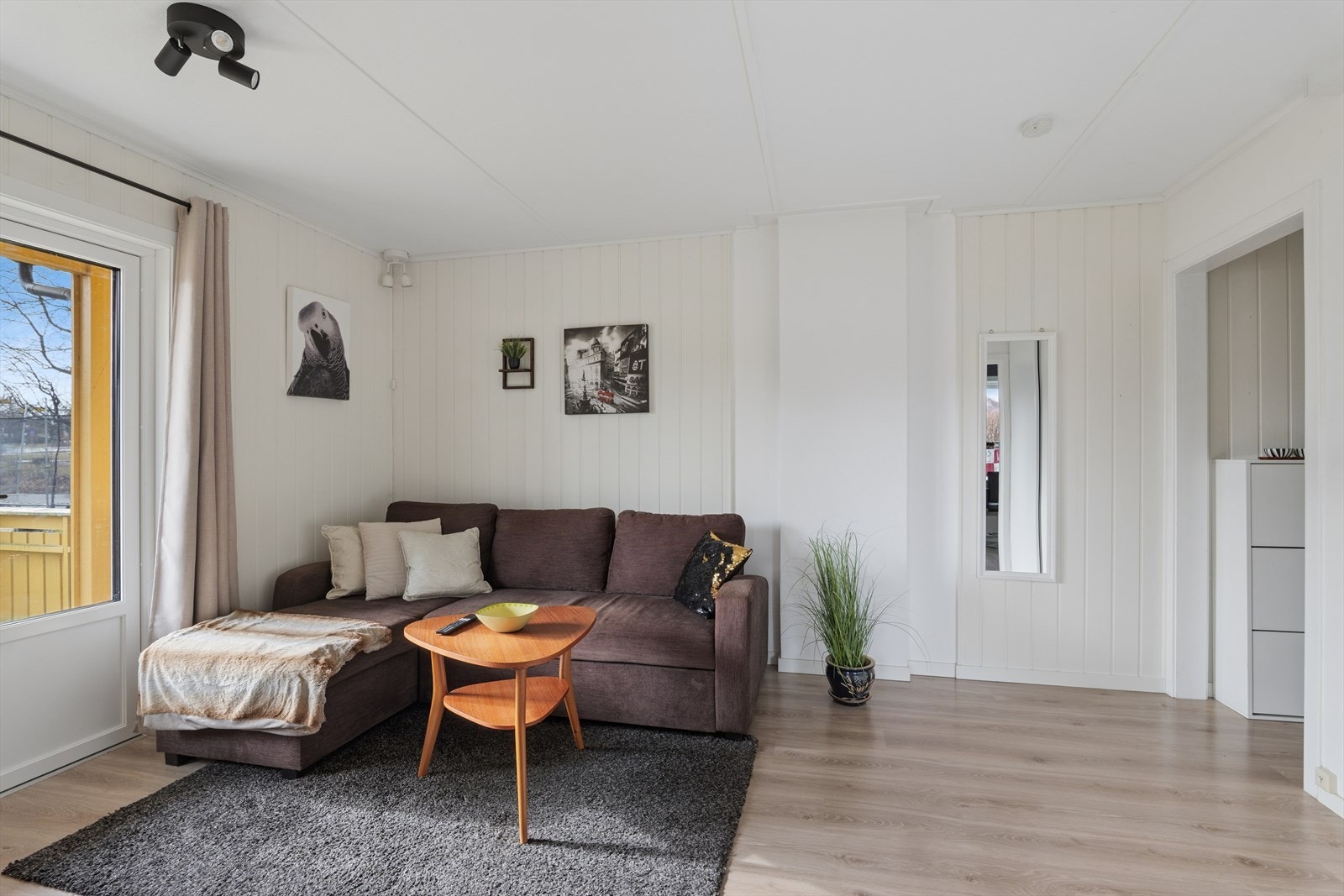 Fra entrè kommer man videre inn i stue - som har lettstelt laminat på gulv og malt panel på vegg Galleribilde
