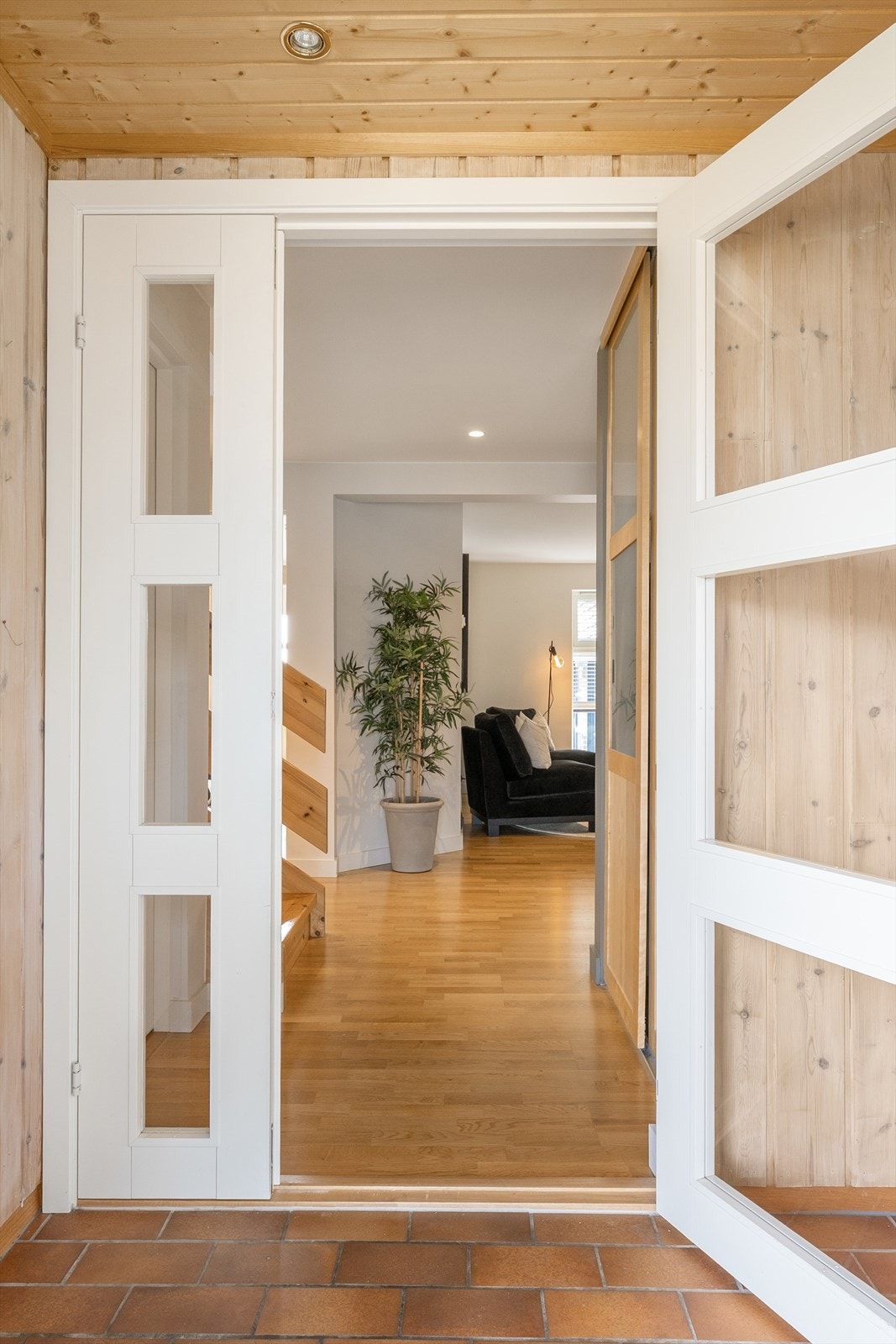 Fra et overbygget inngangsparti kommer du inn i en vindfang med flislagt gulv. En dør med glassfelt åpner videre inn til en romslig hall. Galleribilde