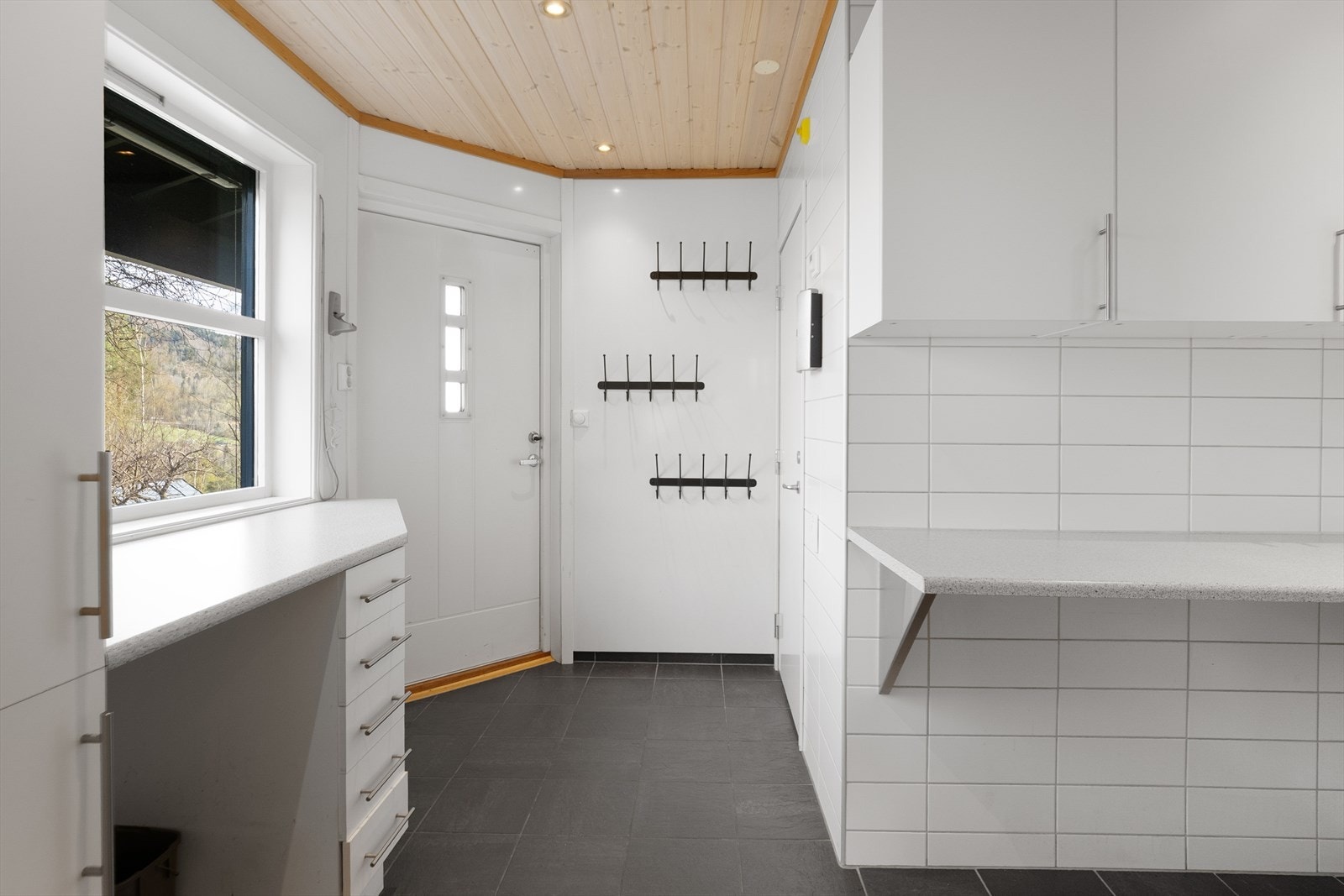 Rommet er innredet med laminert benkeplate, skuffeseksjon og høyskap, samt opplegg for vaskemaskin og utslagsvask. Galleribilde