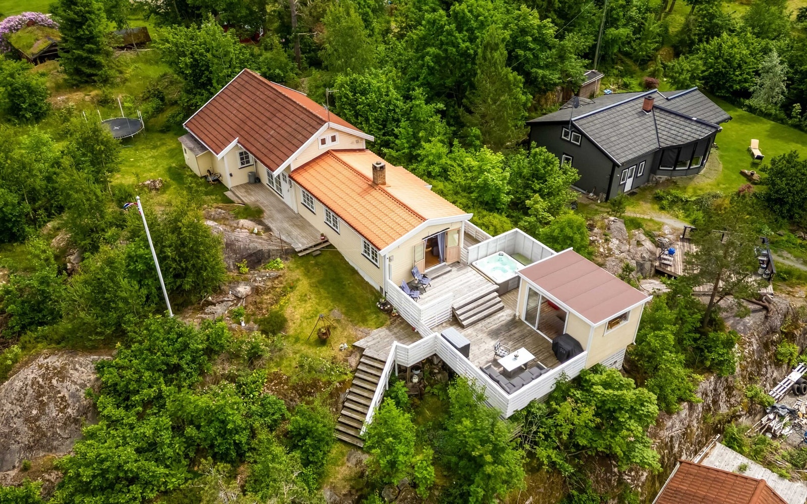 Tomten er romslig og består av plenarealer, naturlige fjellpartier og frodig vegetasjon som skaper en skjermet og privat atmosfære. Galleribilde