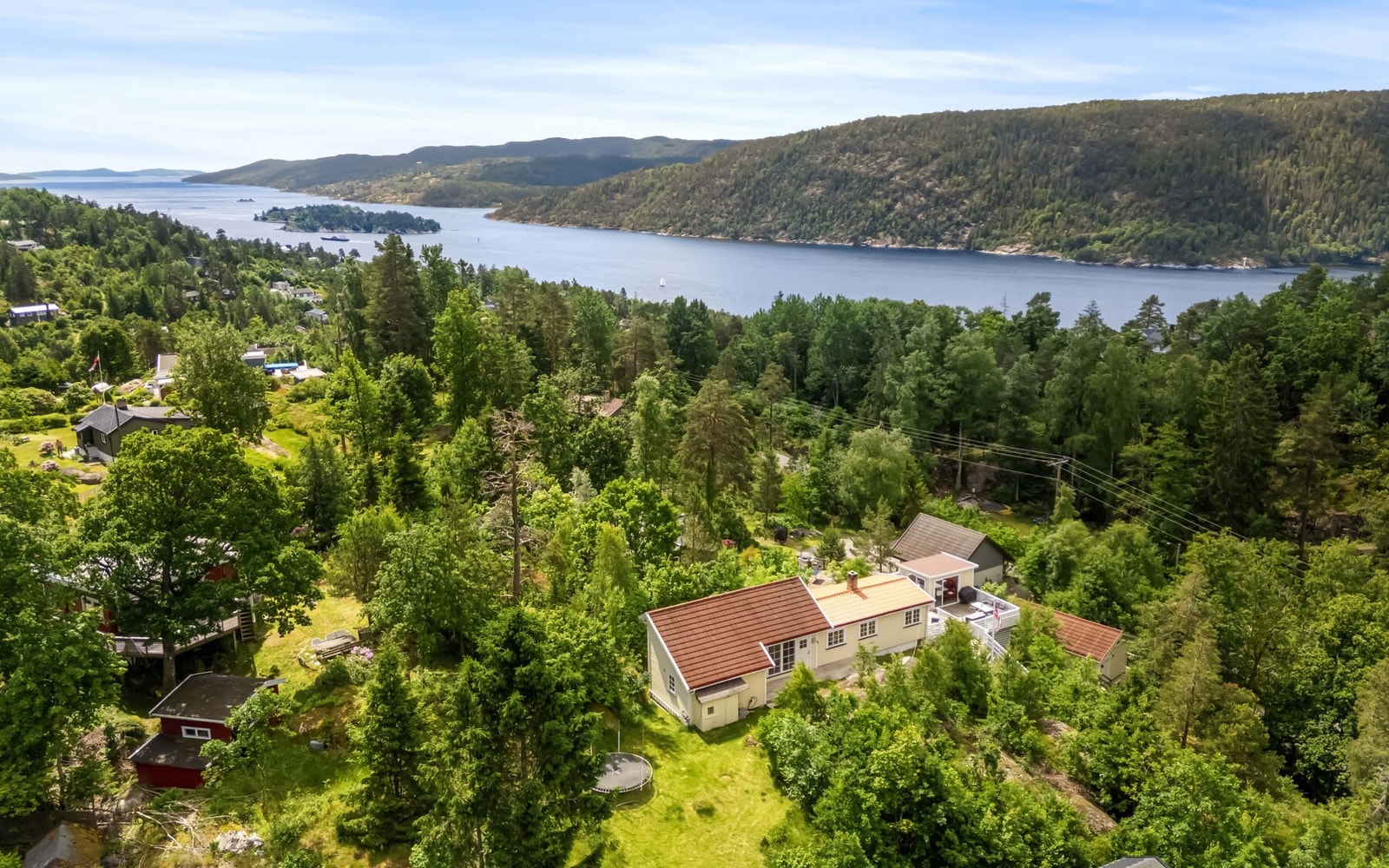 Tomten er romslig og består av plenarealer, naturlige fjellpartier og frodig vegetasjon som skaper en skjermet og privat atmosfære. Galleribilde