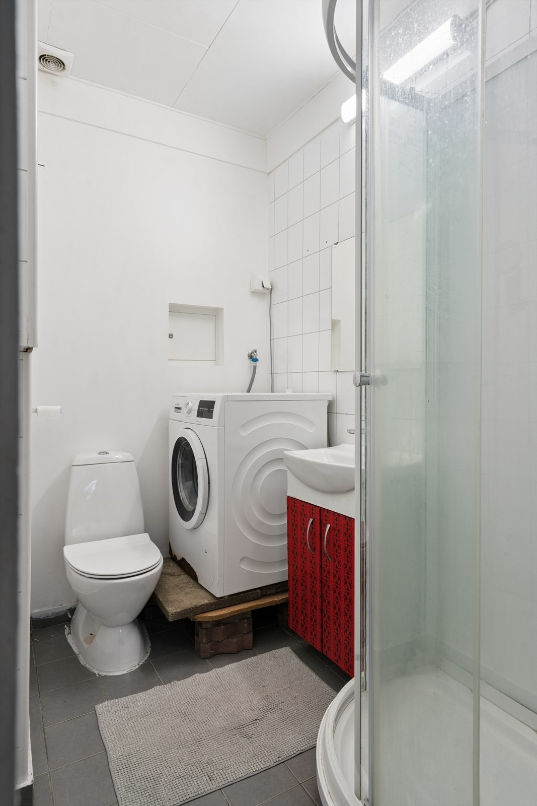 Dette baderommet er utstyrt med dusjkabinett, servant, gulvstående toalett og opplegg for vaskemaskin. Galleribilde