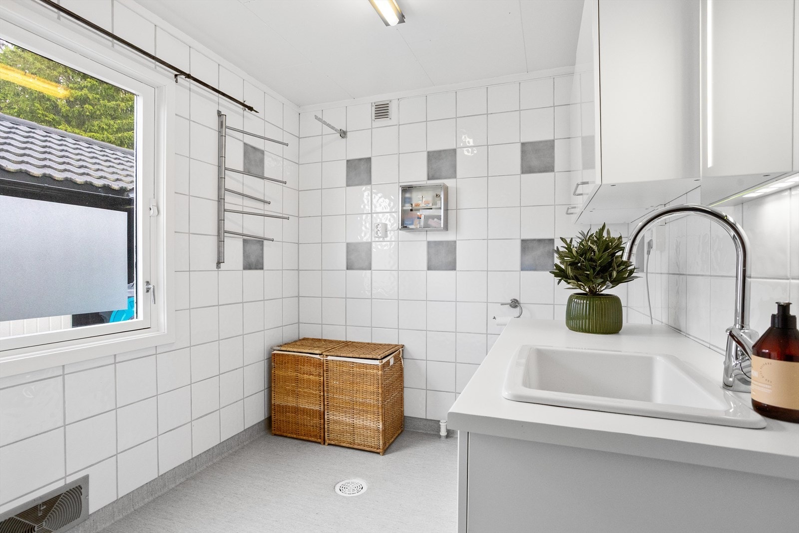 Et romslig og funksjonelt vaskerom med god arbeidsplass, praktiske oppbevaringsløsninger og plass til hverdagens gjøremål. Galleribilde